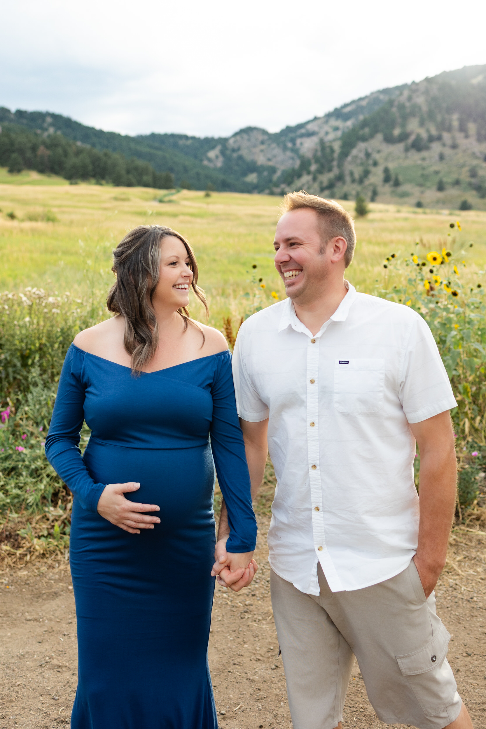 Husband and wife walk and laugh together while holding hands.
