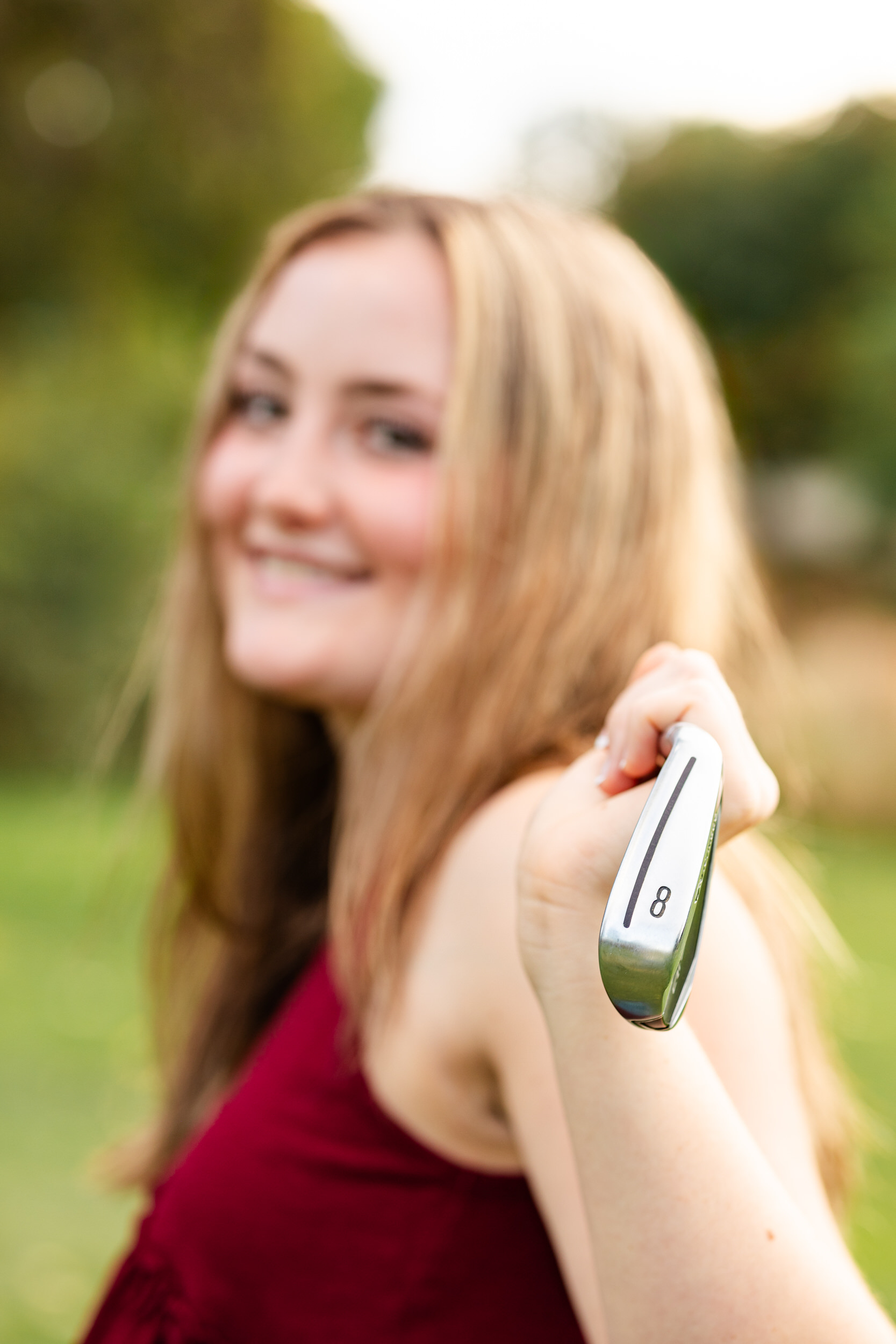Close up of a putter and the young woman holding it is blurred in the background.