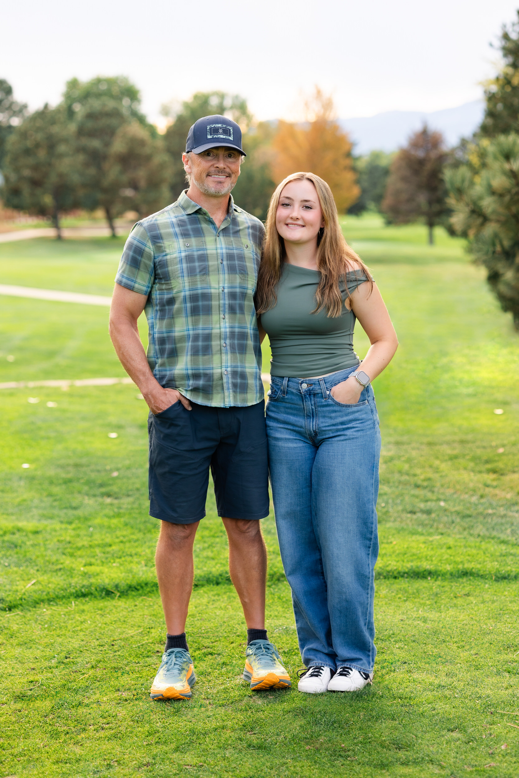 A young woman and her dad smile at the camera.