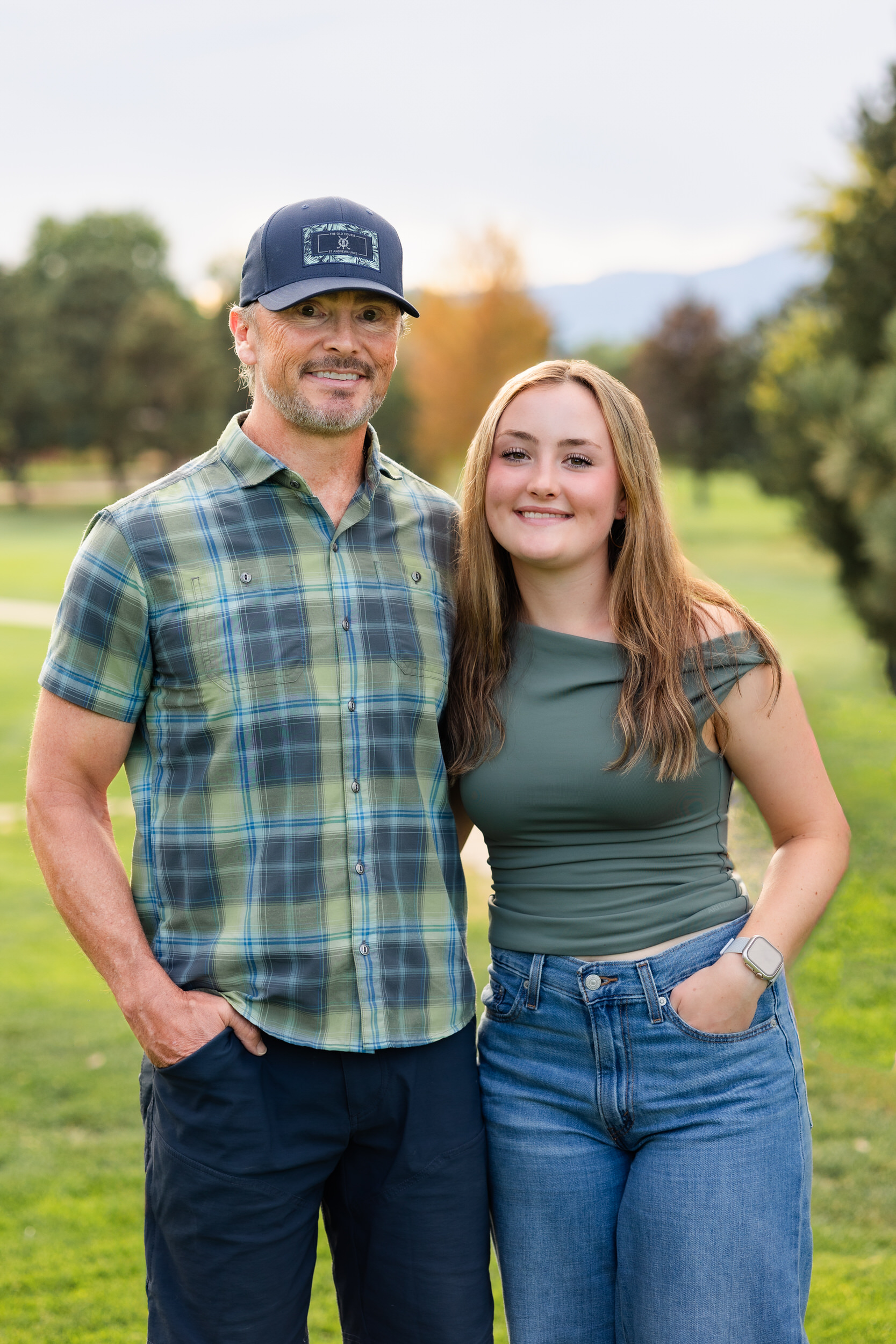 A young woman and her dad smile at the camera.
