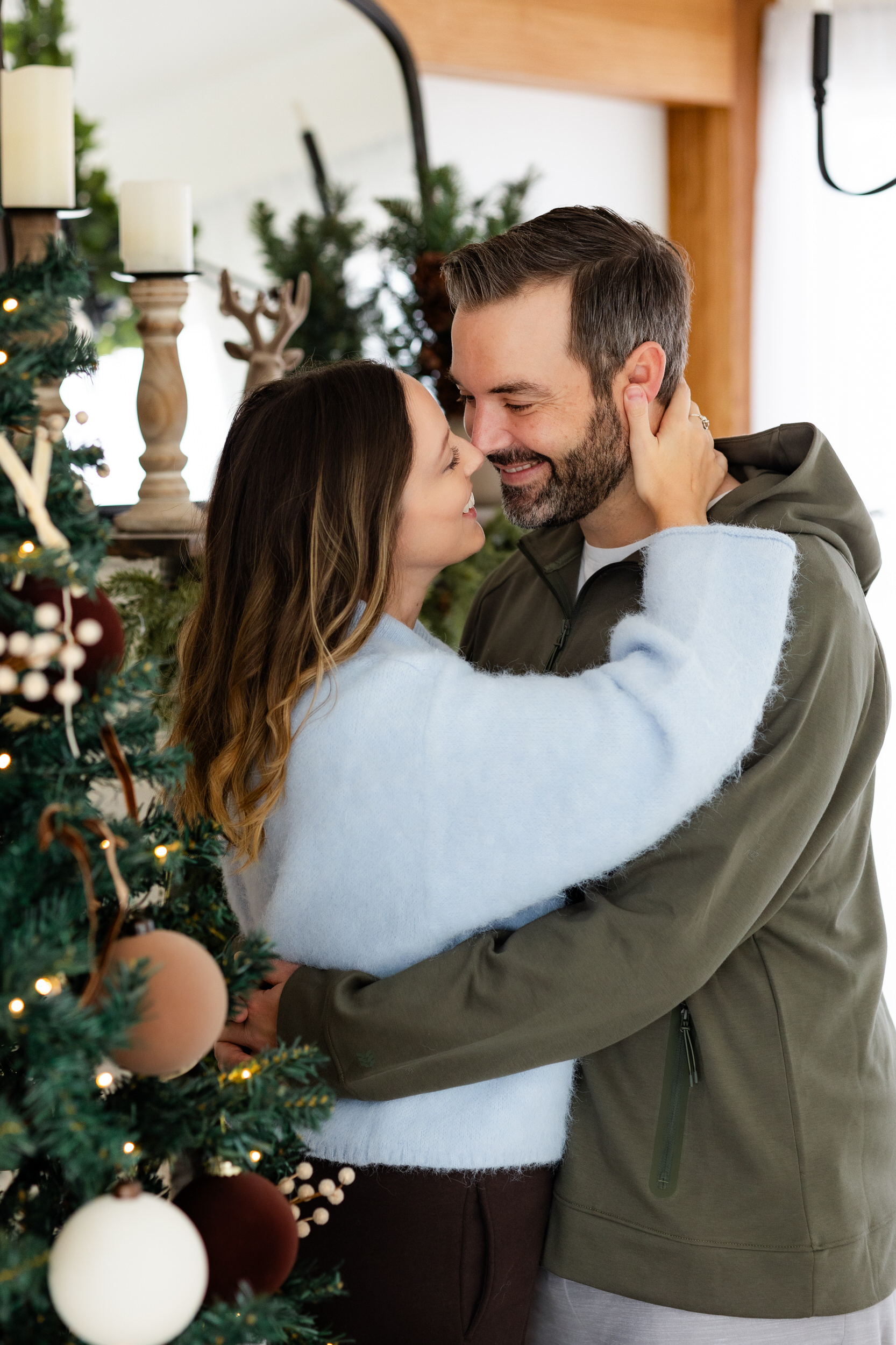 Mom and dad share a kiss next to the Christmas tree.