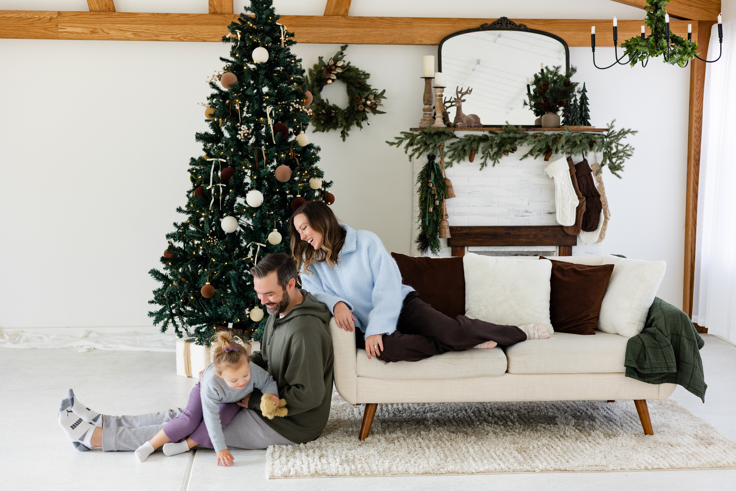 Little girl sits in dad's lap while mom and dad smile at her.