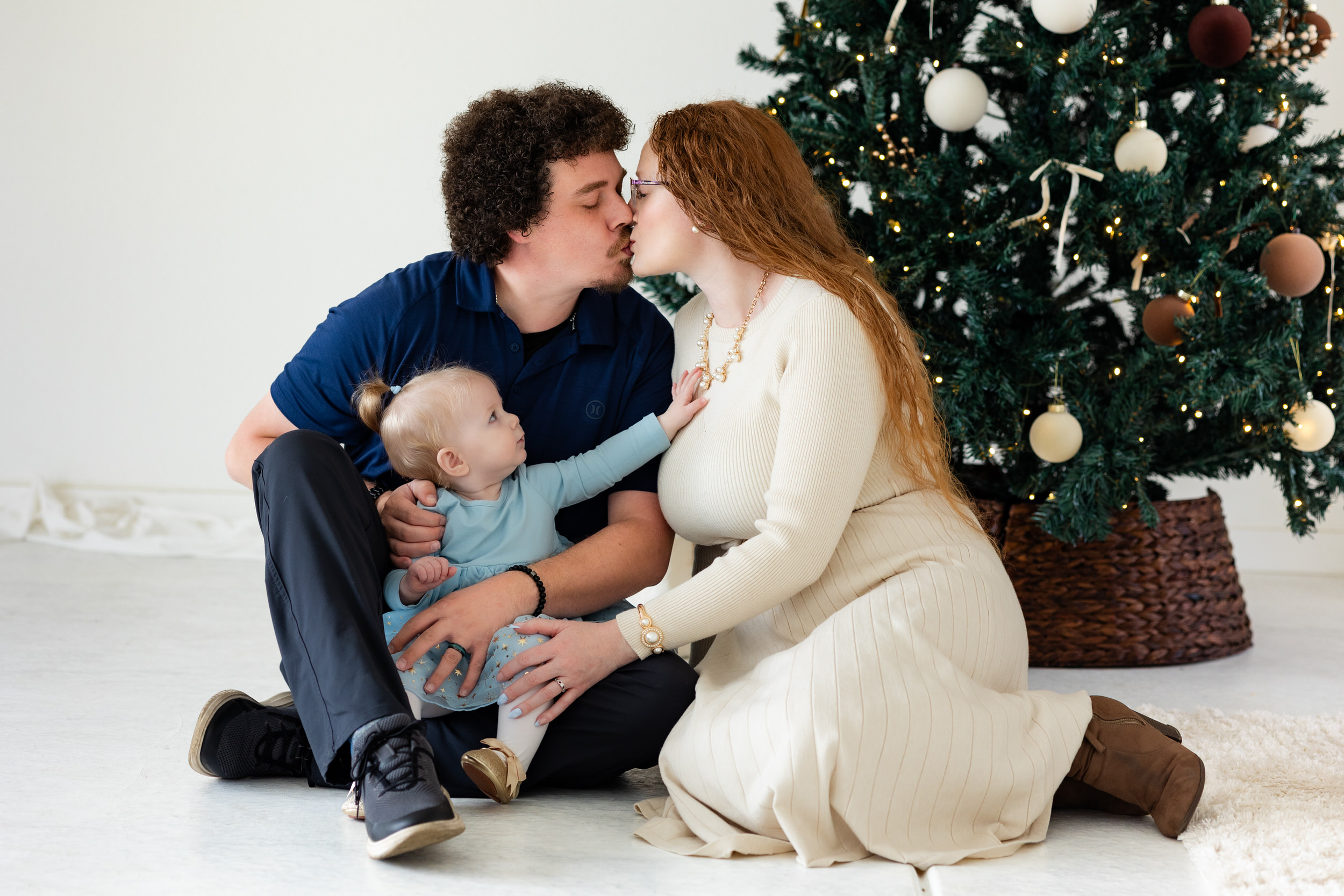Mom and dad kiss while baby girl looks at mom.