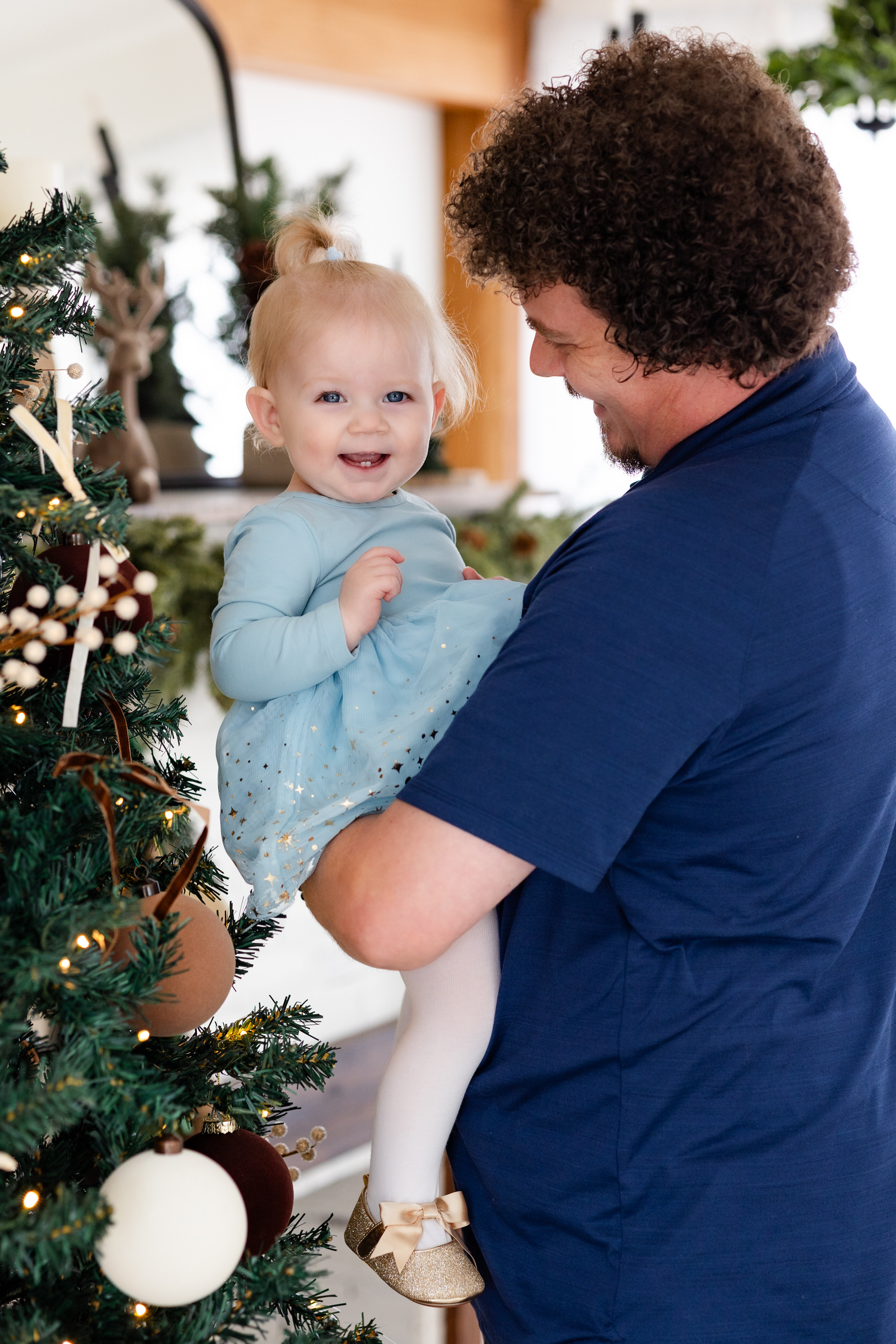 Dad holds baby girl and smiles at her while she smiles at camera.