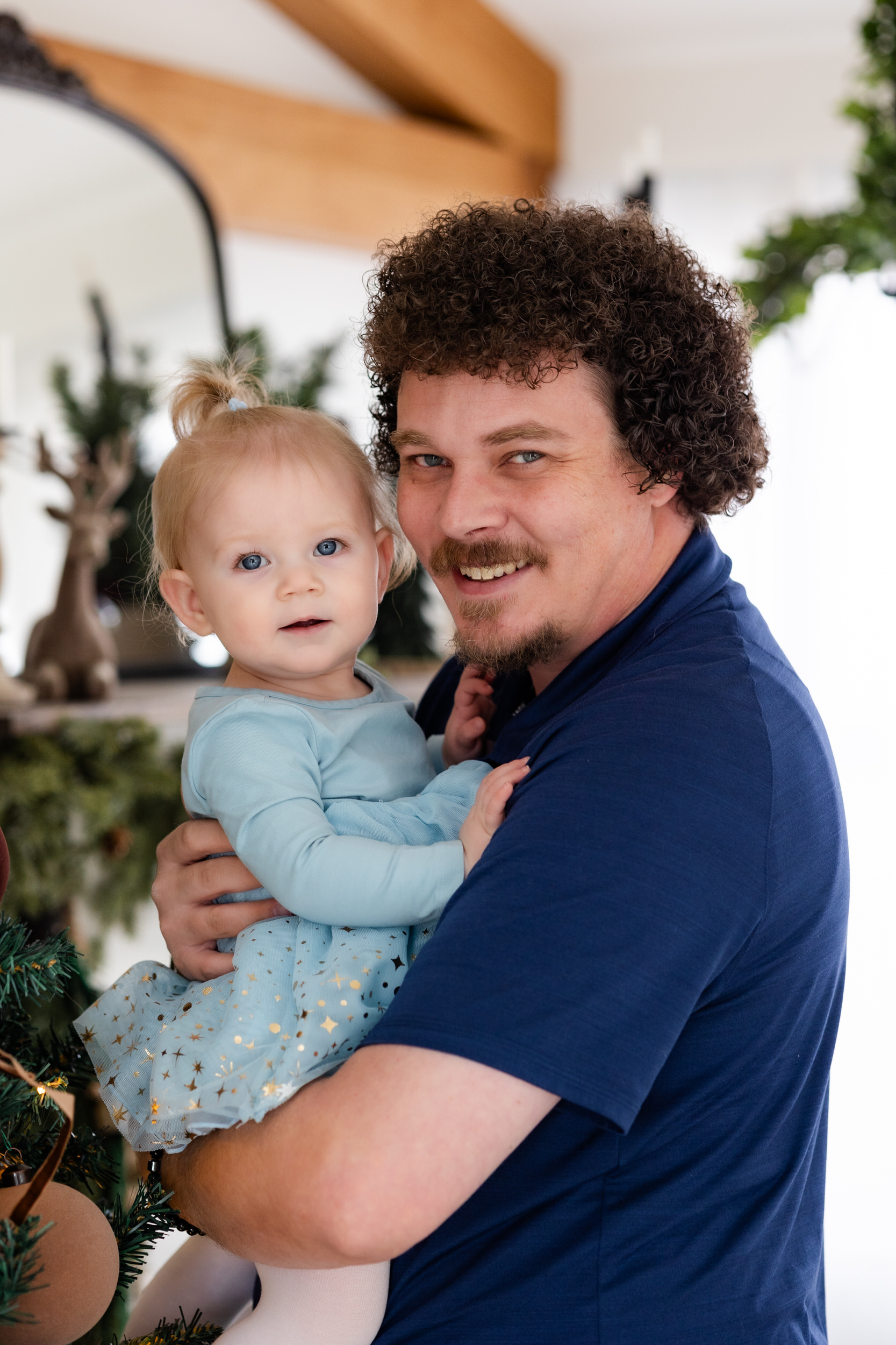 Dad holds baby girl and they both smile at the camera.
