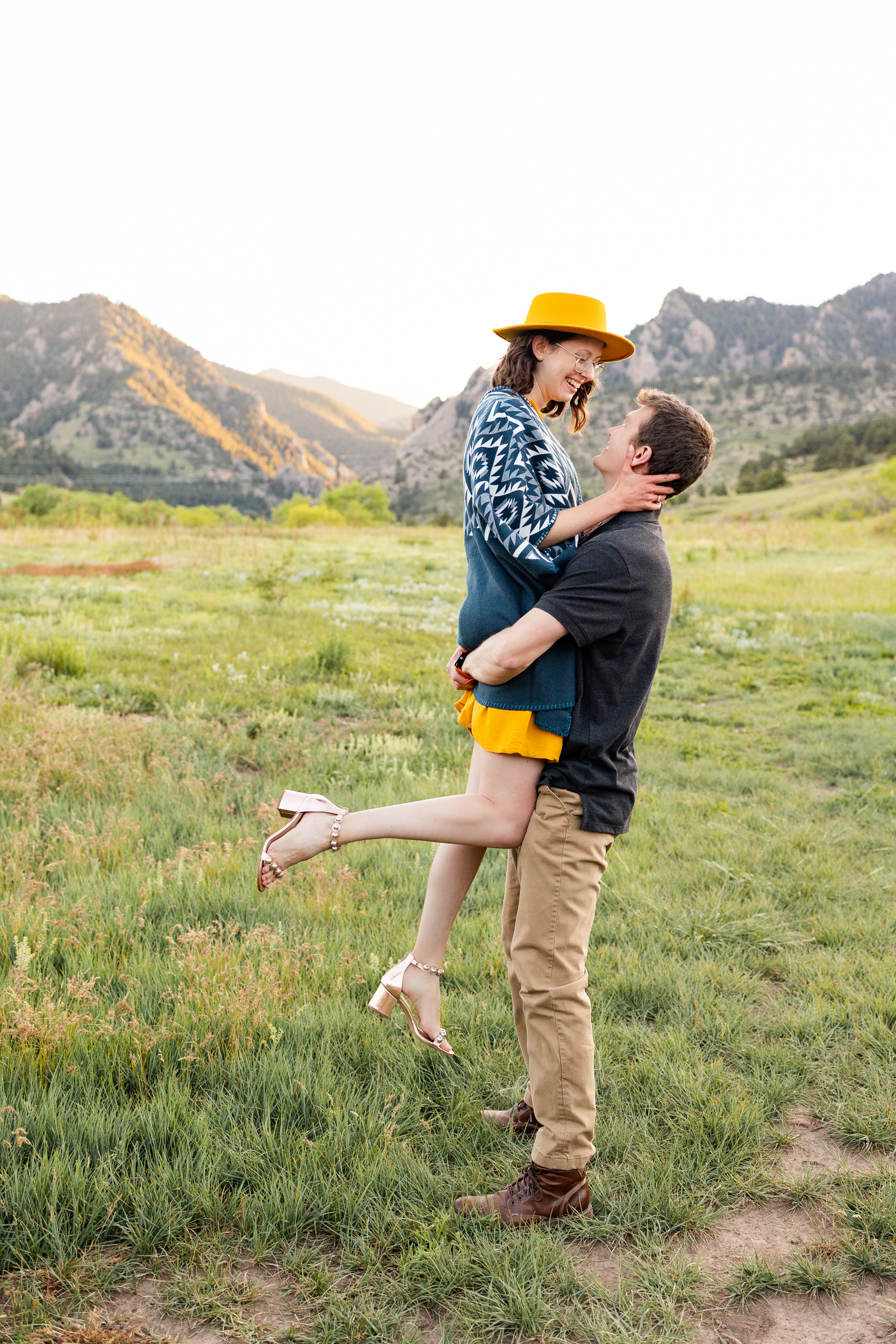 A man lifts his wife in the air as she looks down at him and smiles.