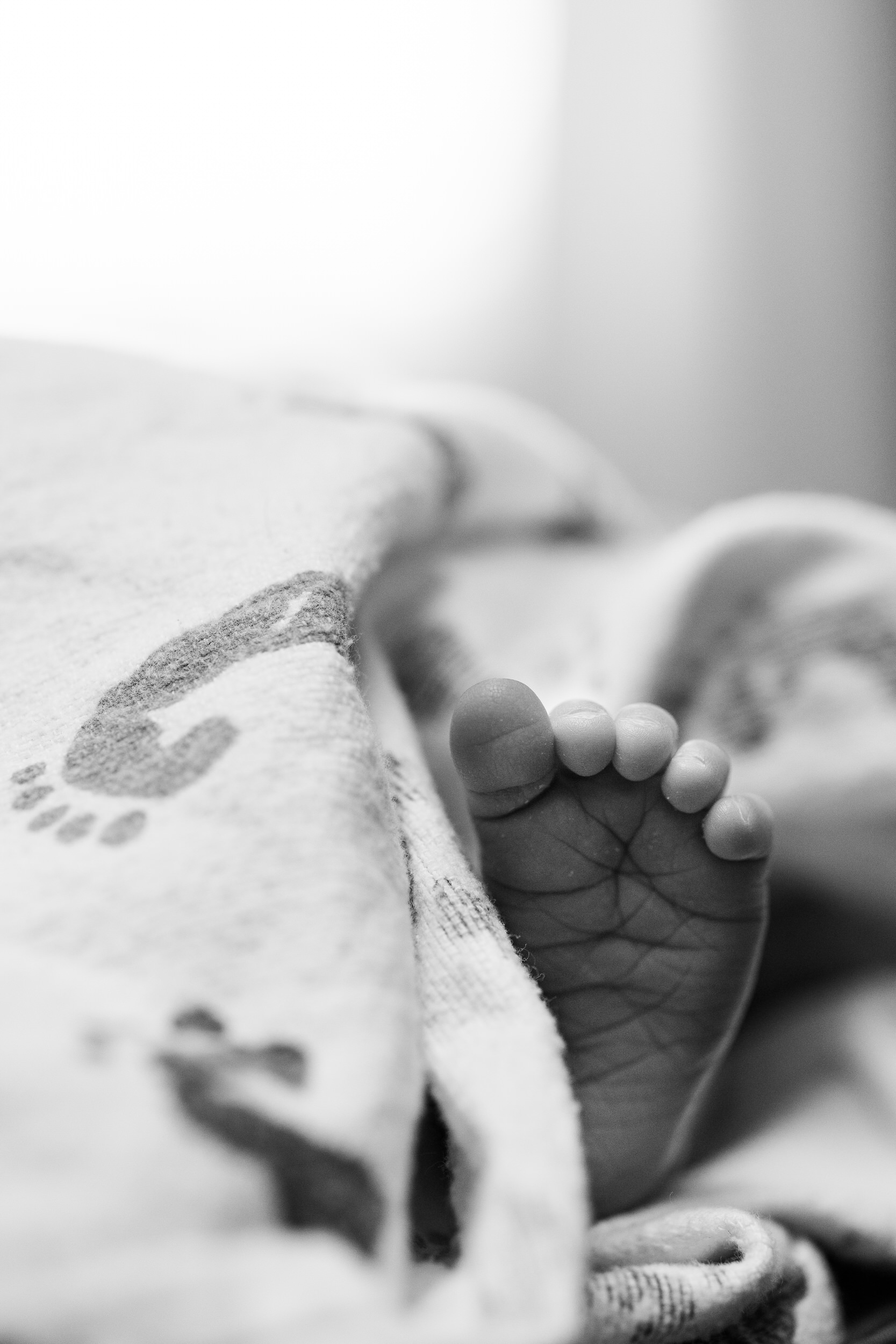 A baby's foot sticks out of a hospital blanket.