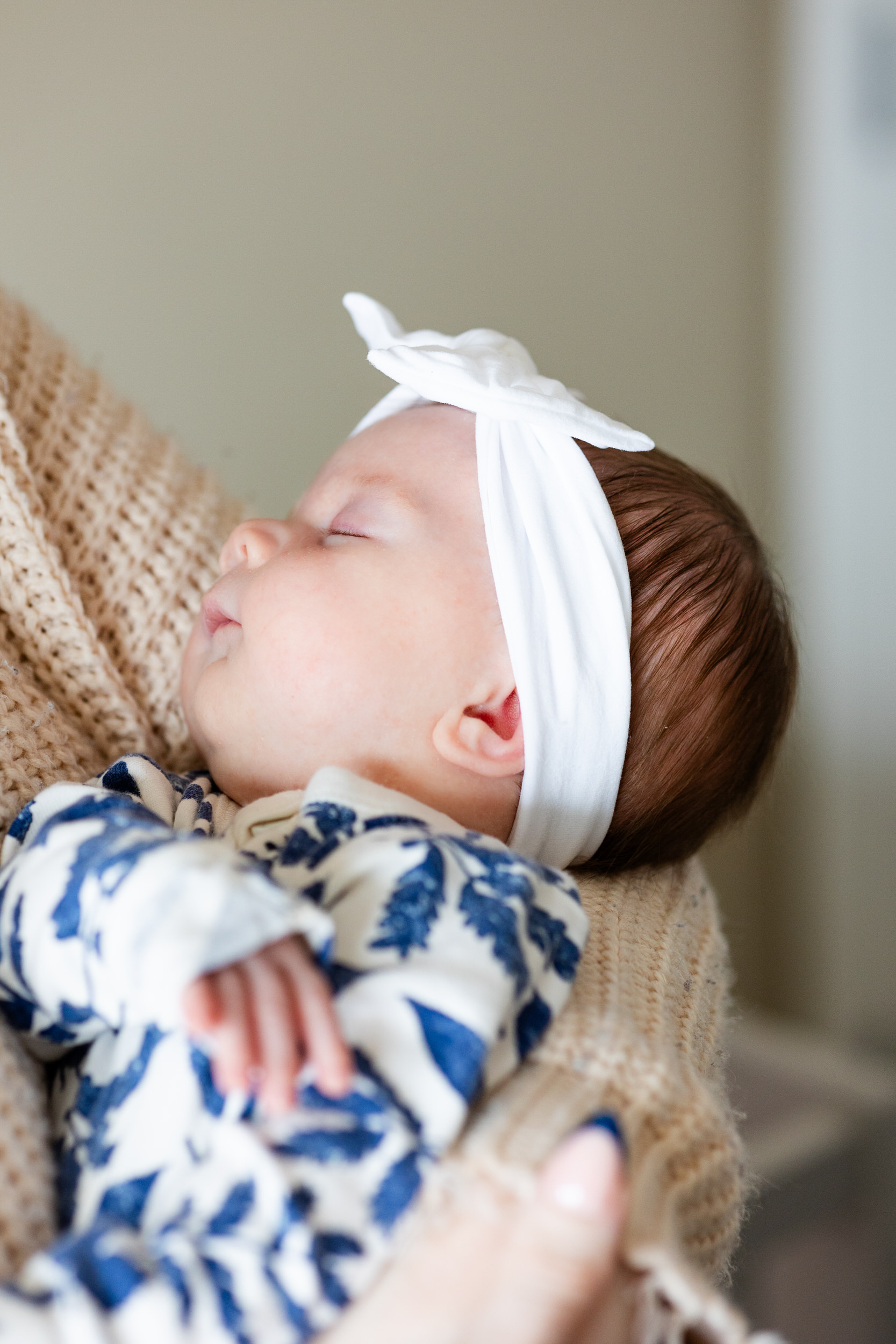 A baby girl sleeps in her mom's arms.