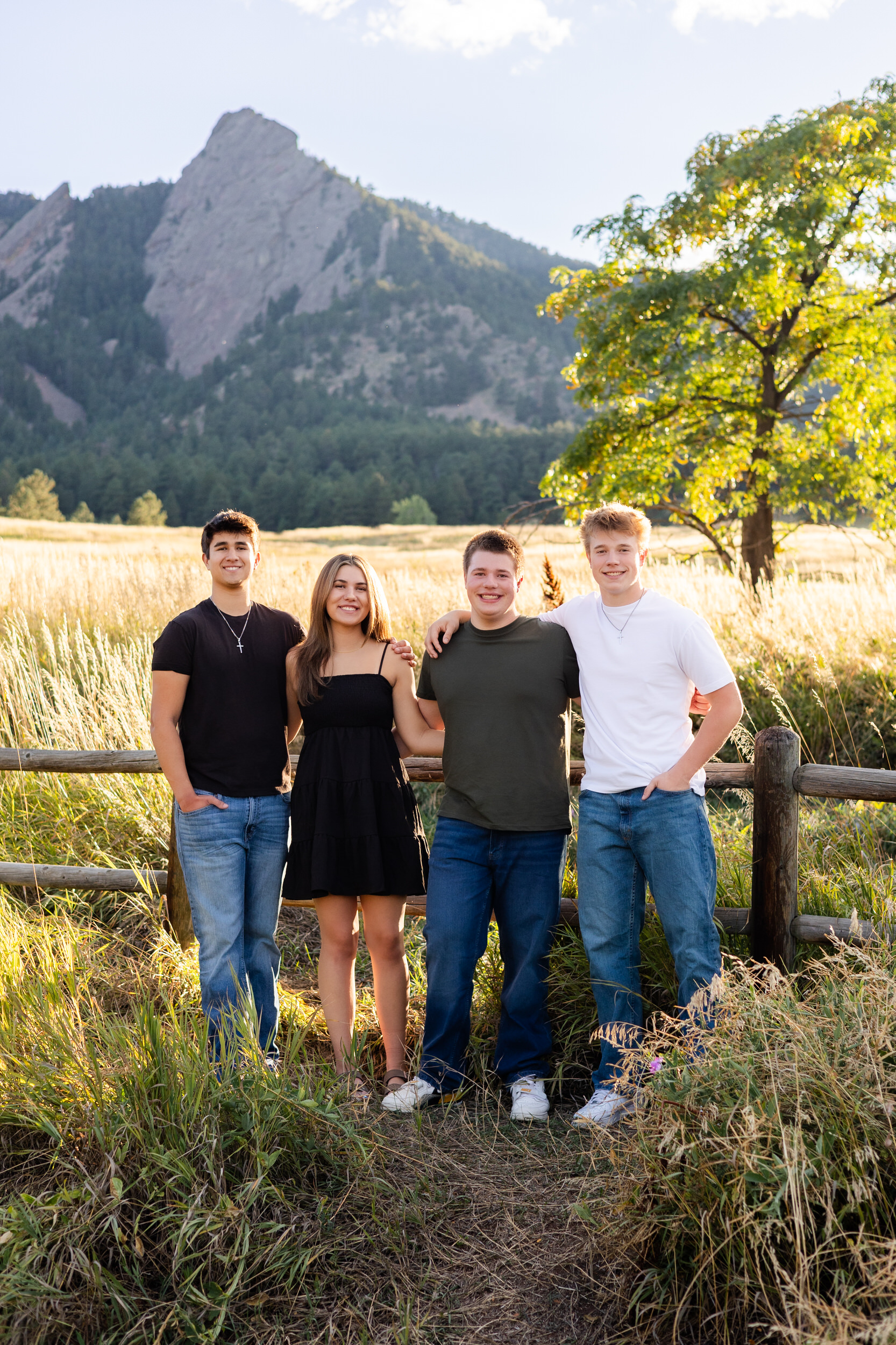 Four young adult cousins stand with their arms around each other's shoulders and smile at the camera.