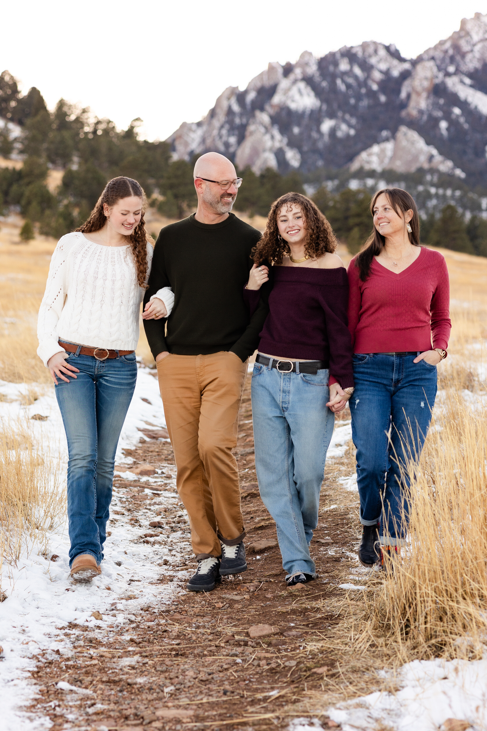 A family of four walks arm-in-arm and laughs together.