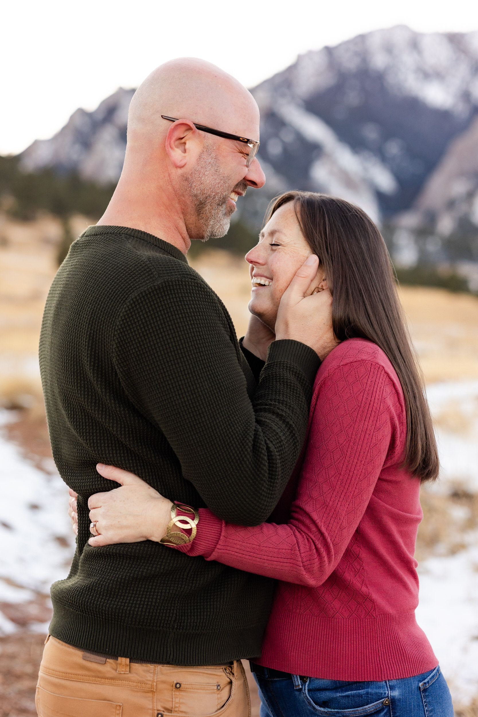 Husband and wife laugh with each other right before they lean in for a kiss.