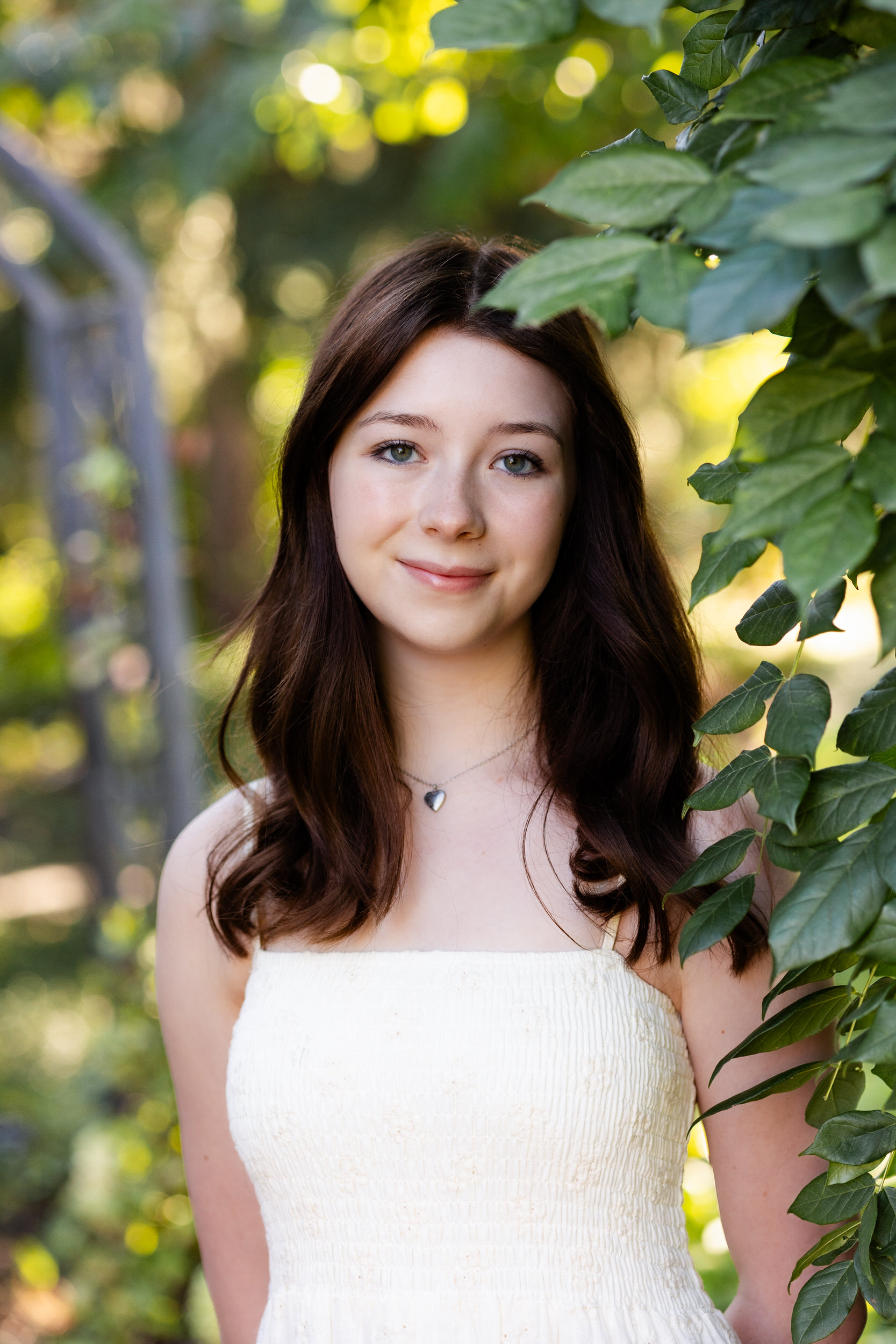 A young woman stands under an archway with greenery at the Denver Botanic Gardens.