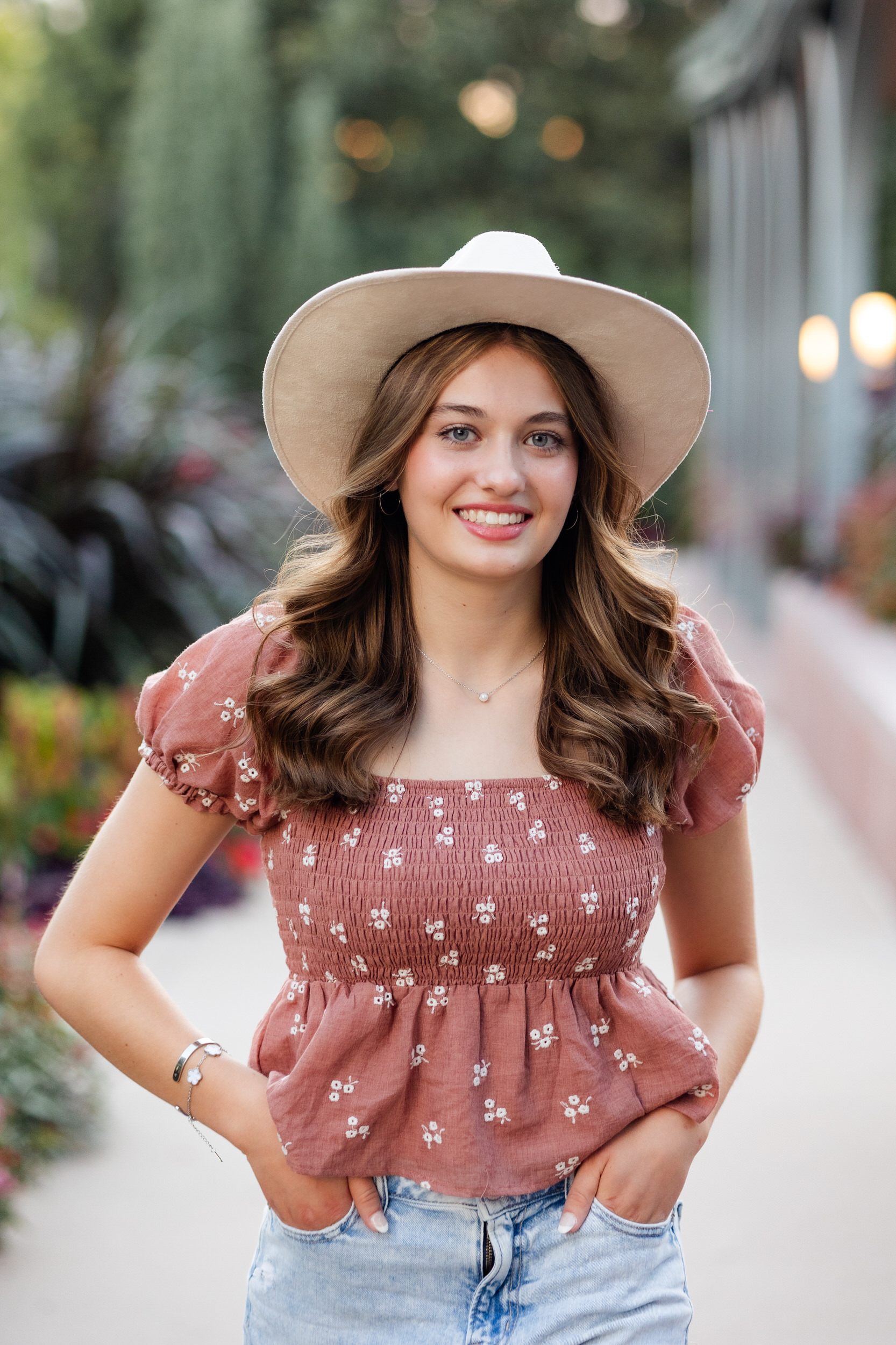 A young woman in a wide-brimmed hat smiles at the camera.