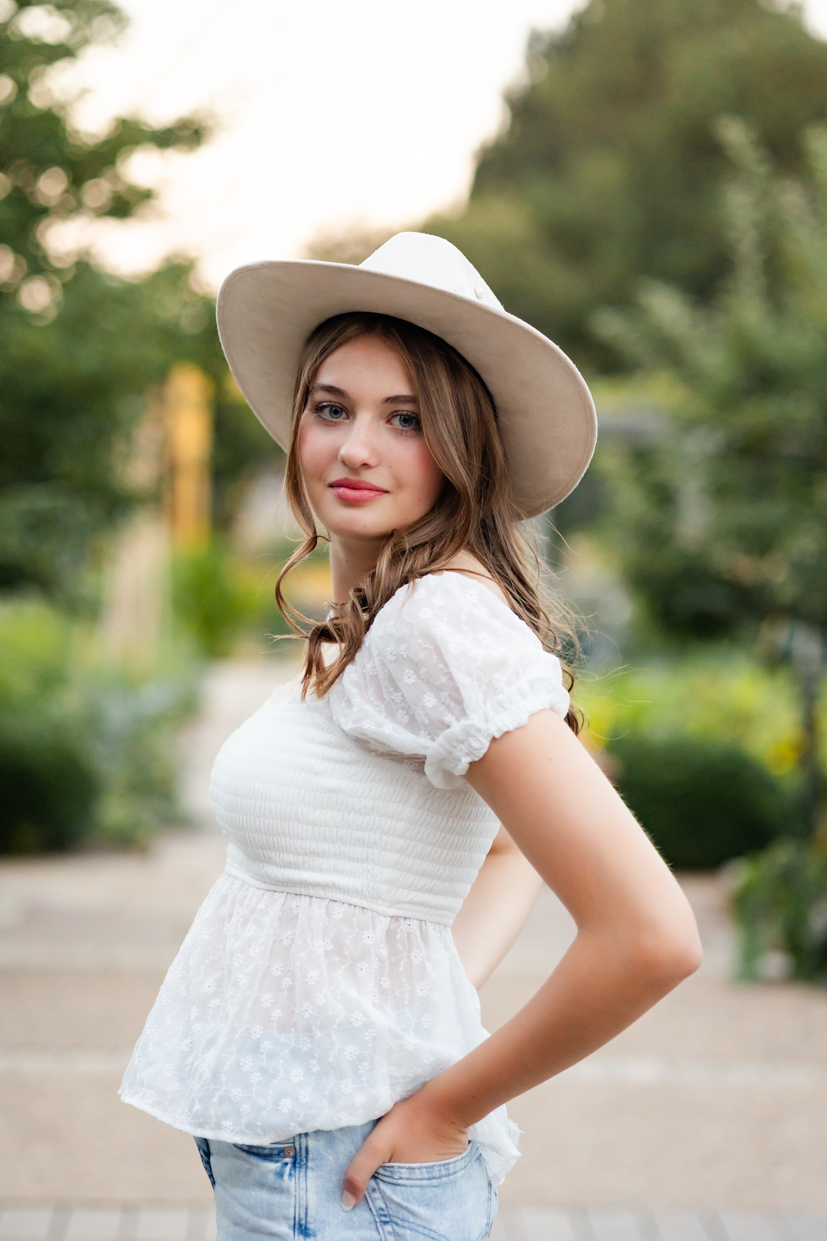 A young woman in a wide-brimmed hat looks at the camera.