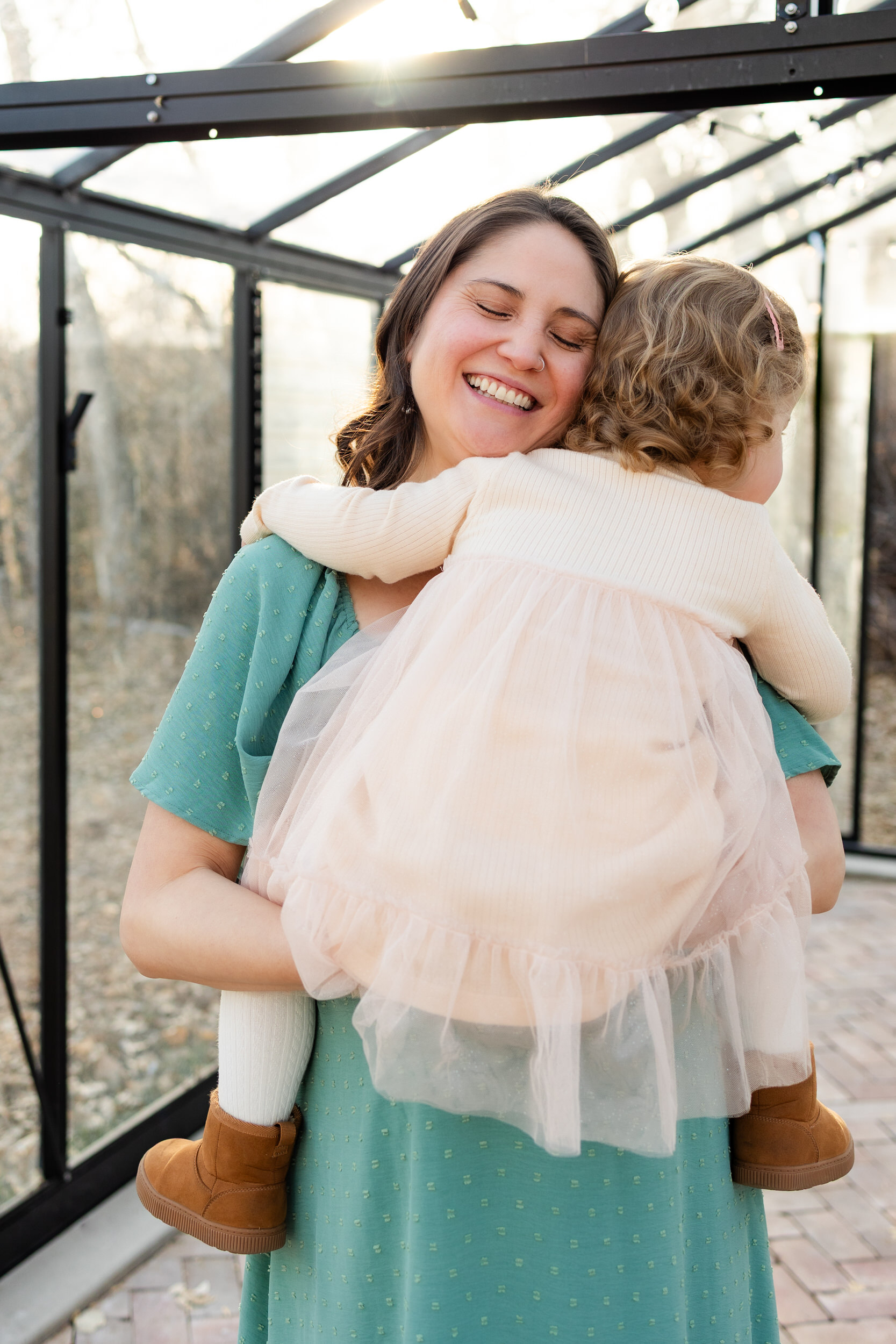 Mom holds her toddler daughter and smiles.