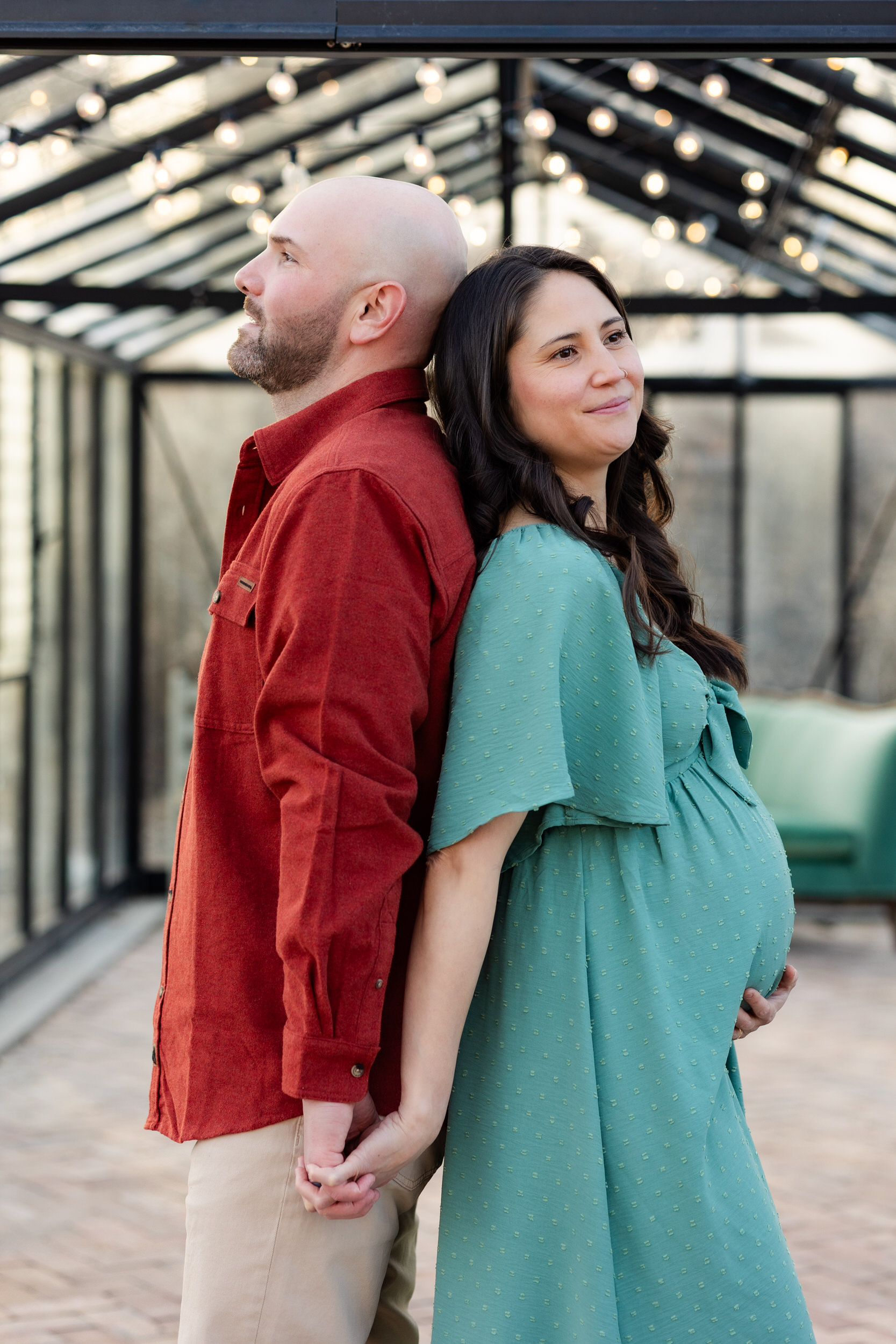 Husband and wife stand back-to-back holding hands.