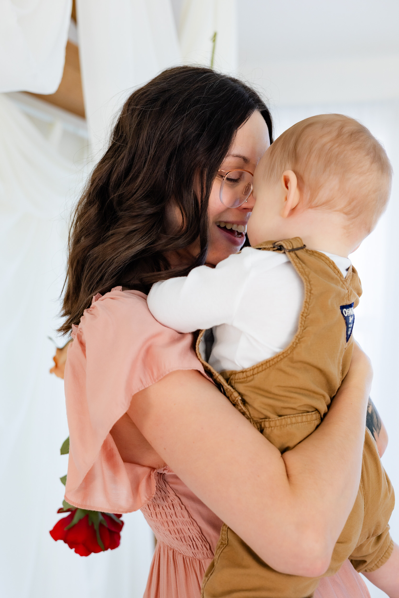 A mom holds her baby and gives him Eskimo kisses.