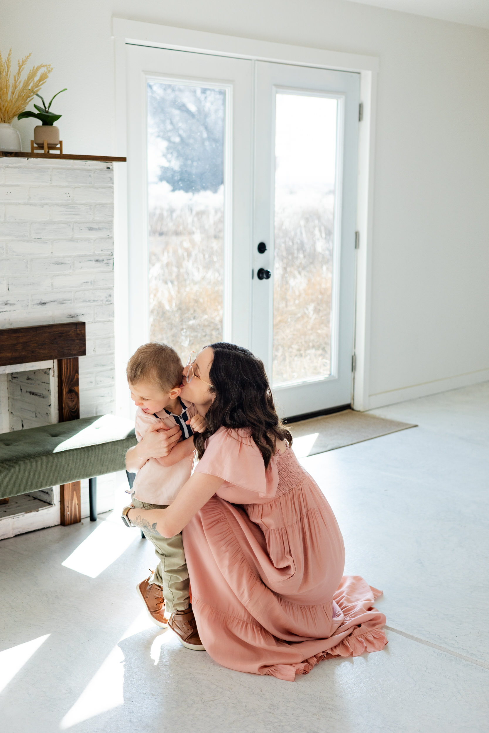 A mom kisses her young son on his cheek.