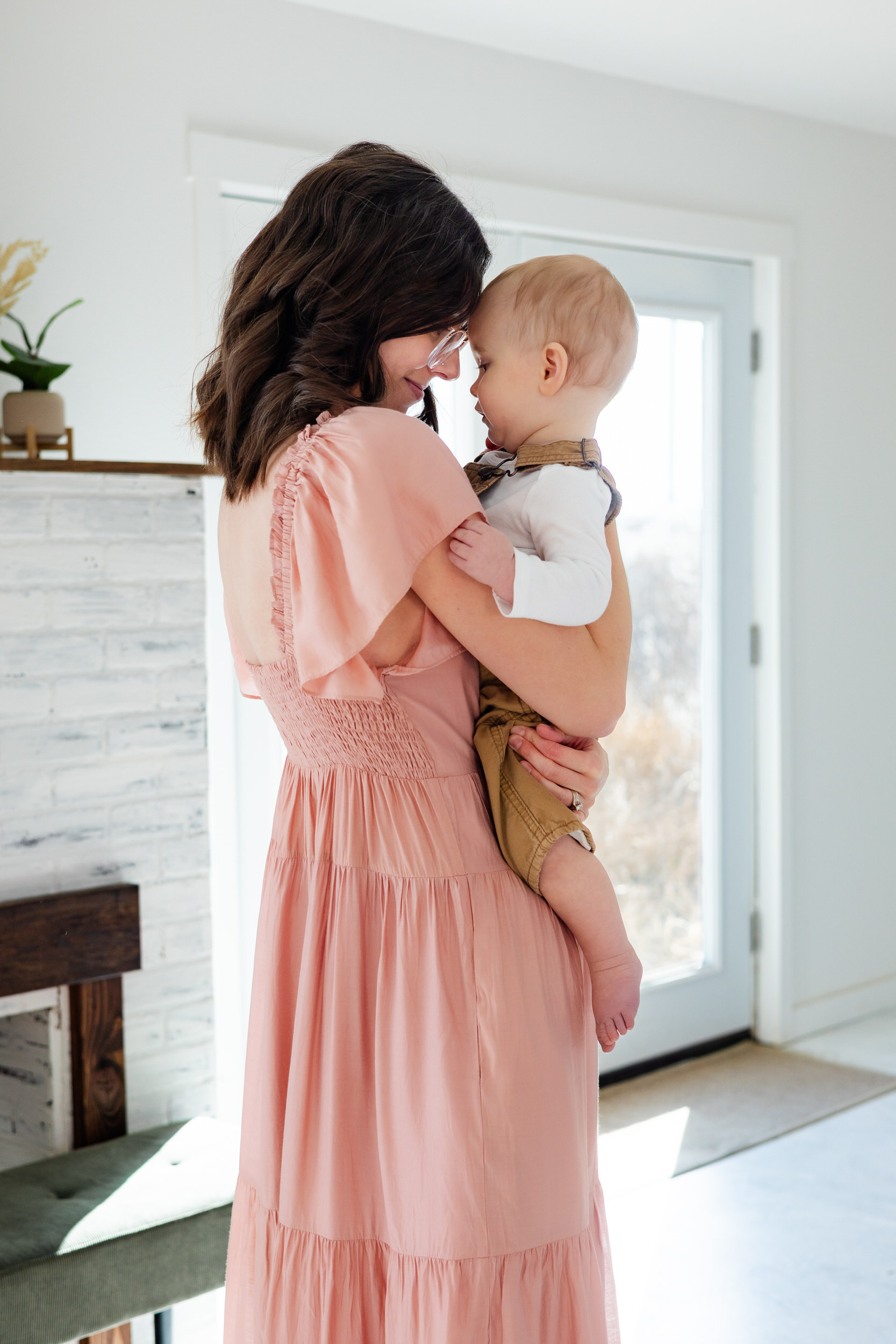 A mom holds her baby and leans her forehead against his.