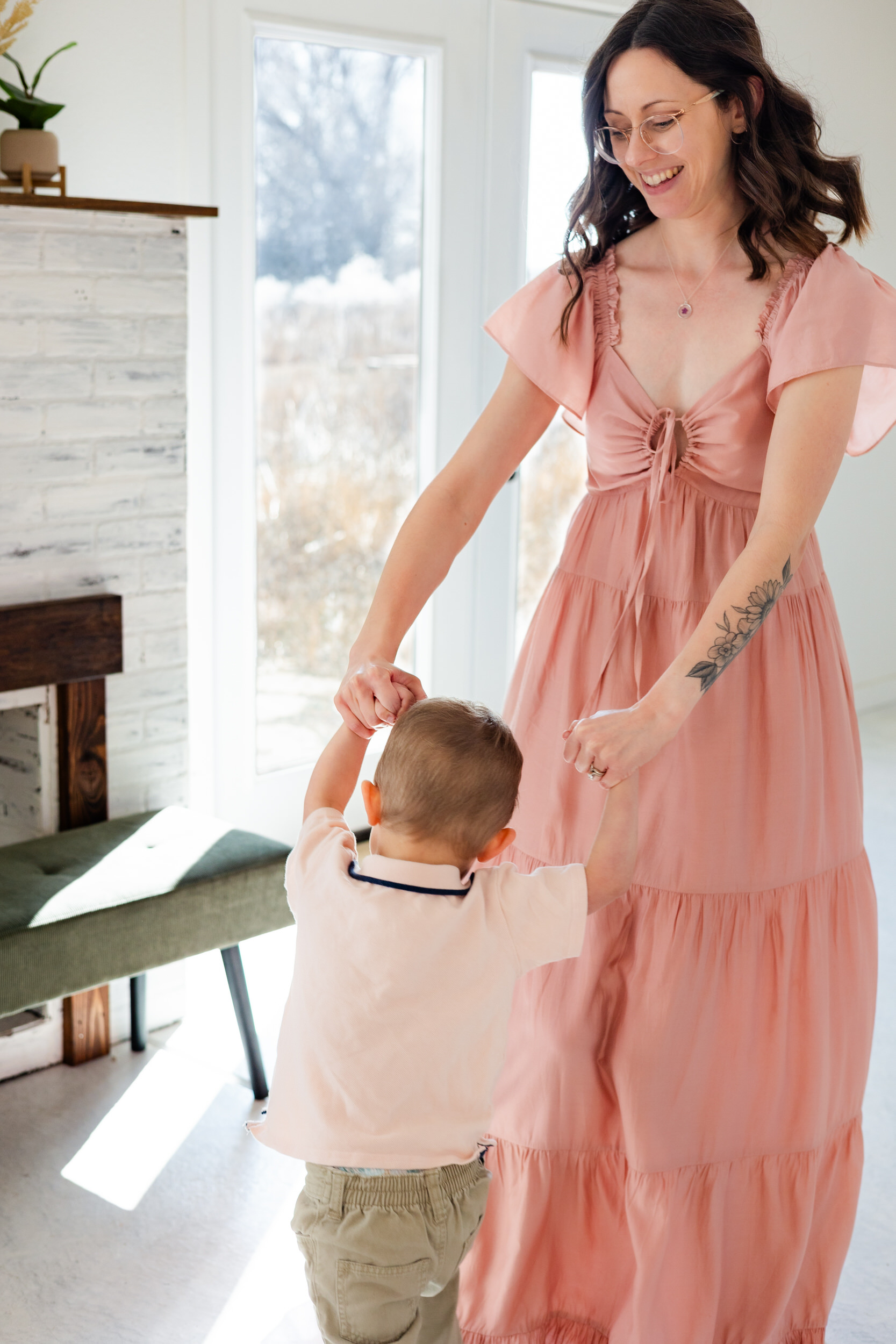 A mom holds her young son's hands as they spin in a circle together.