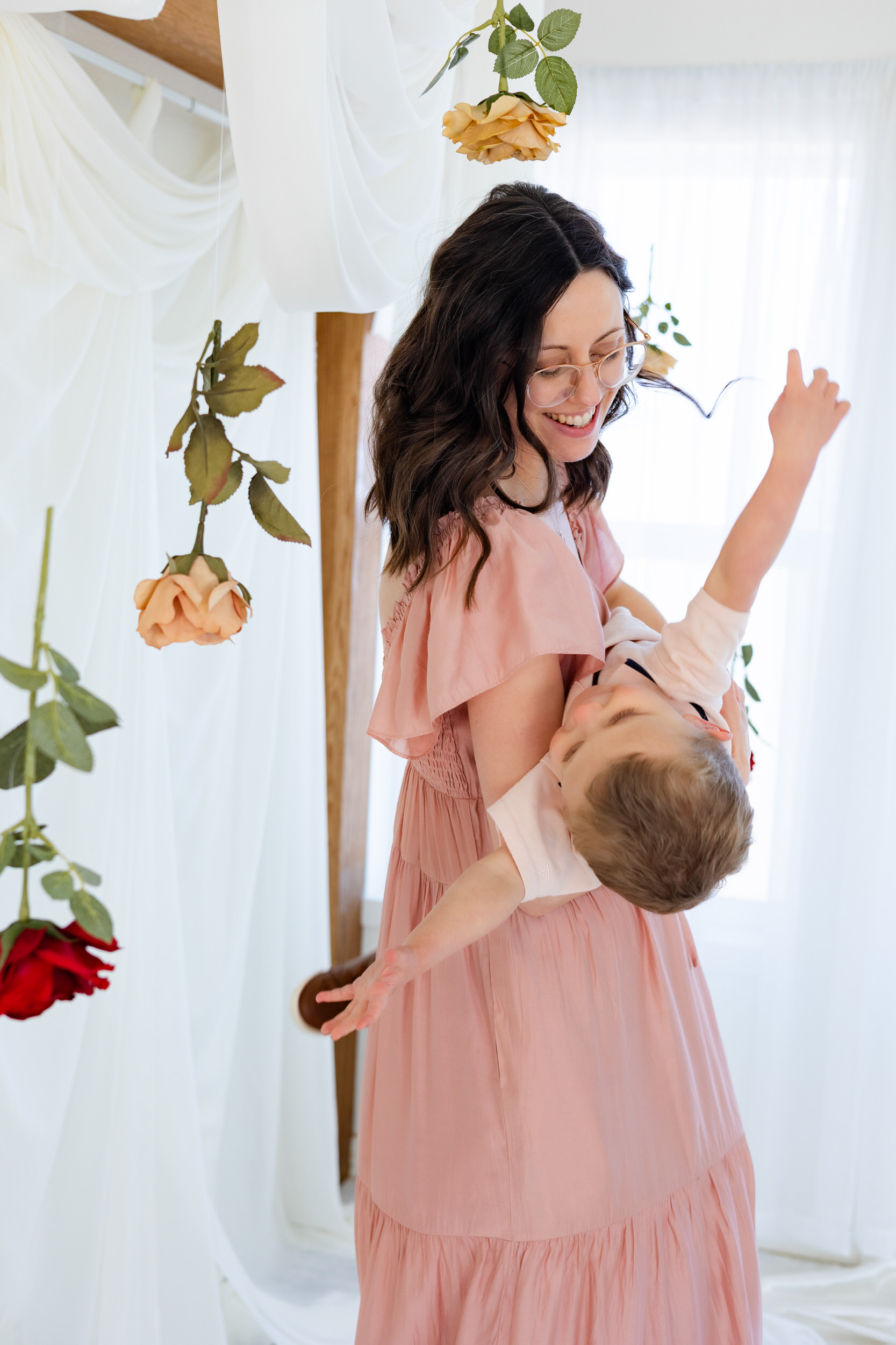 A mom dips her toddler son upside down as he laughs.