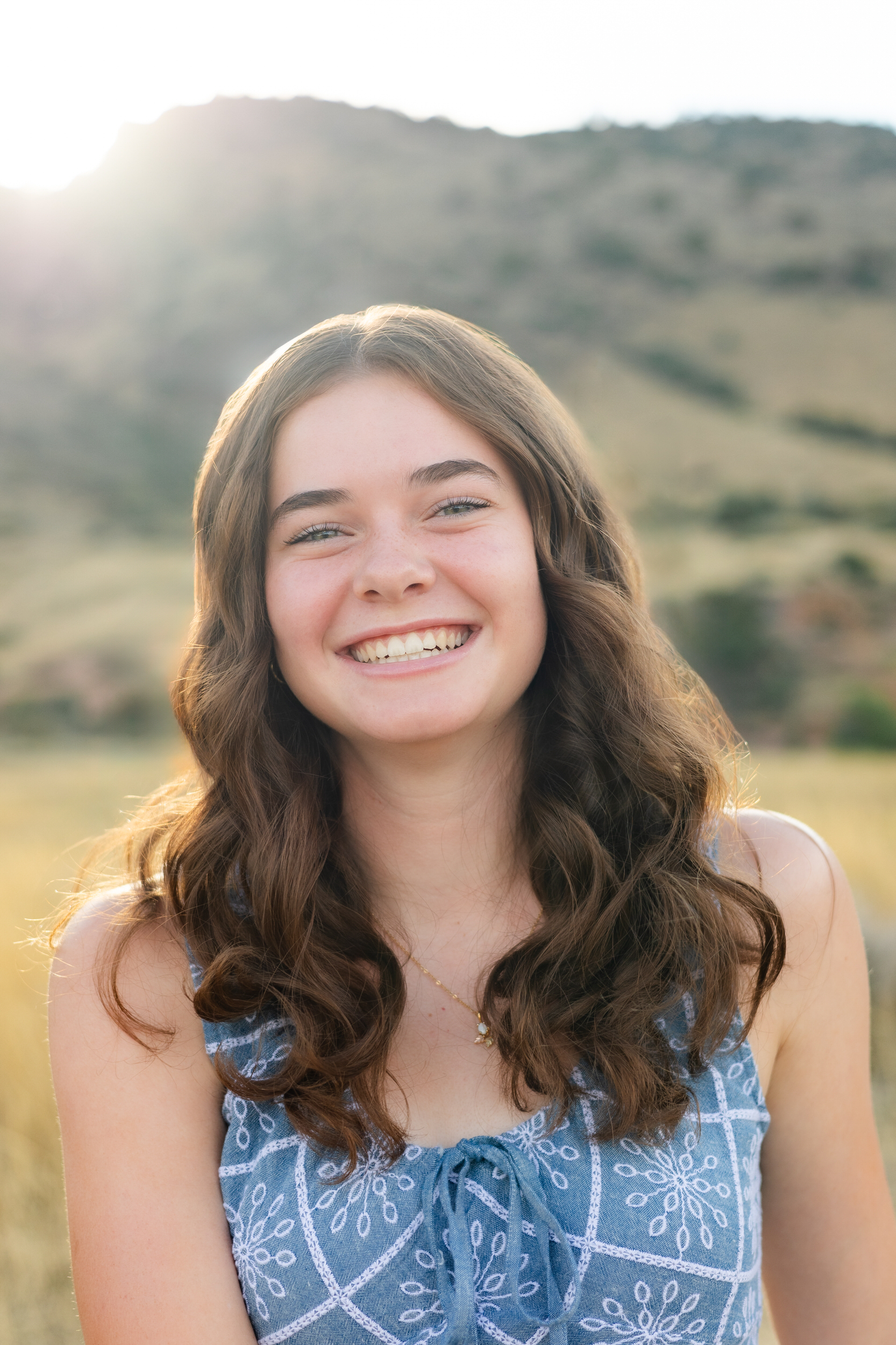 A young woman smiles at the camera during golden hour.
