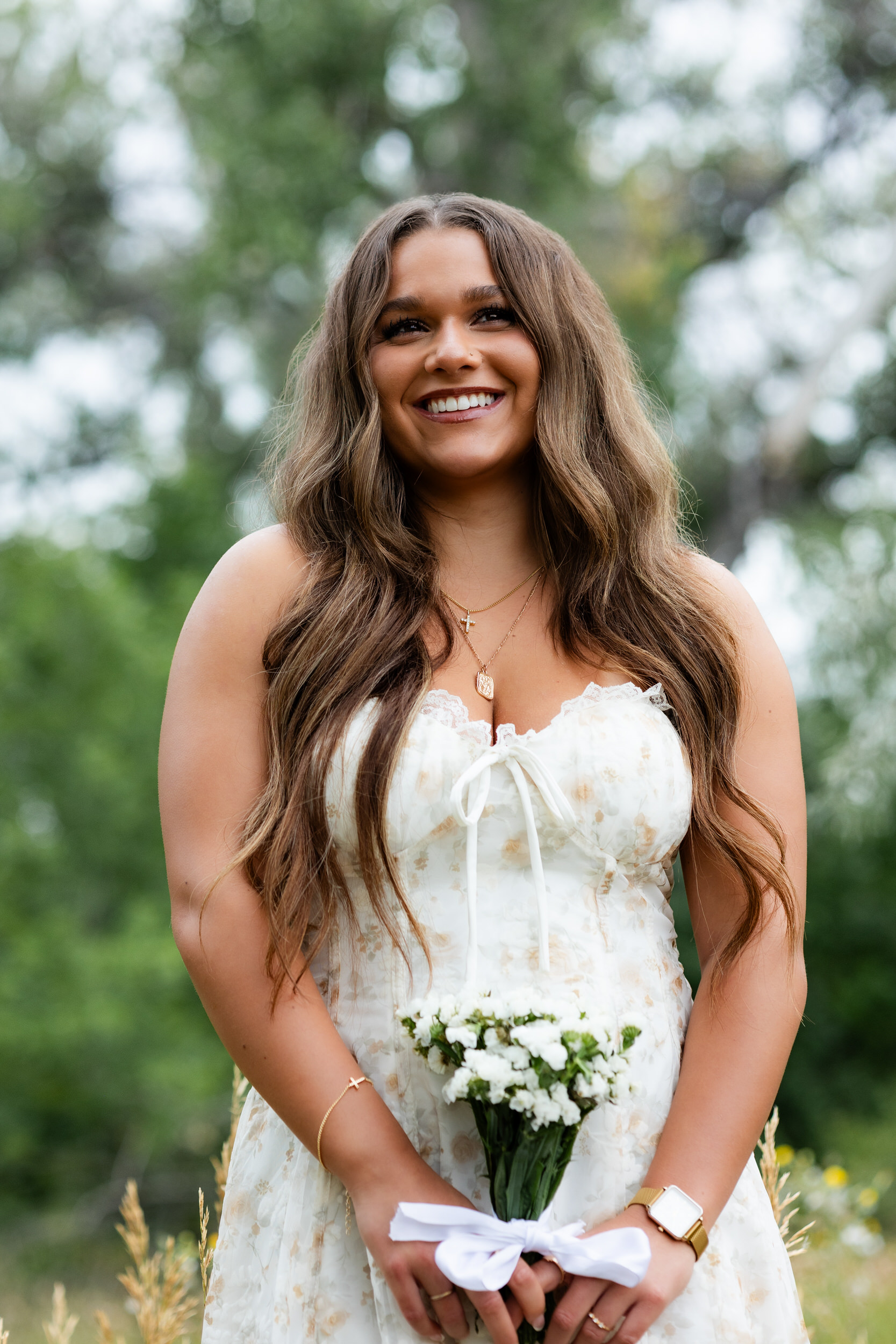 A young woman holding a bouquet smiles.