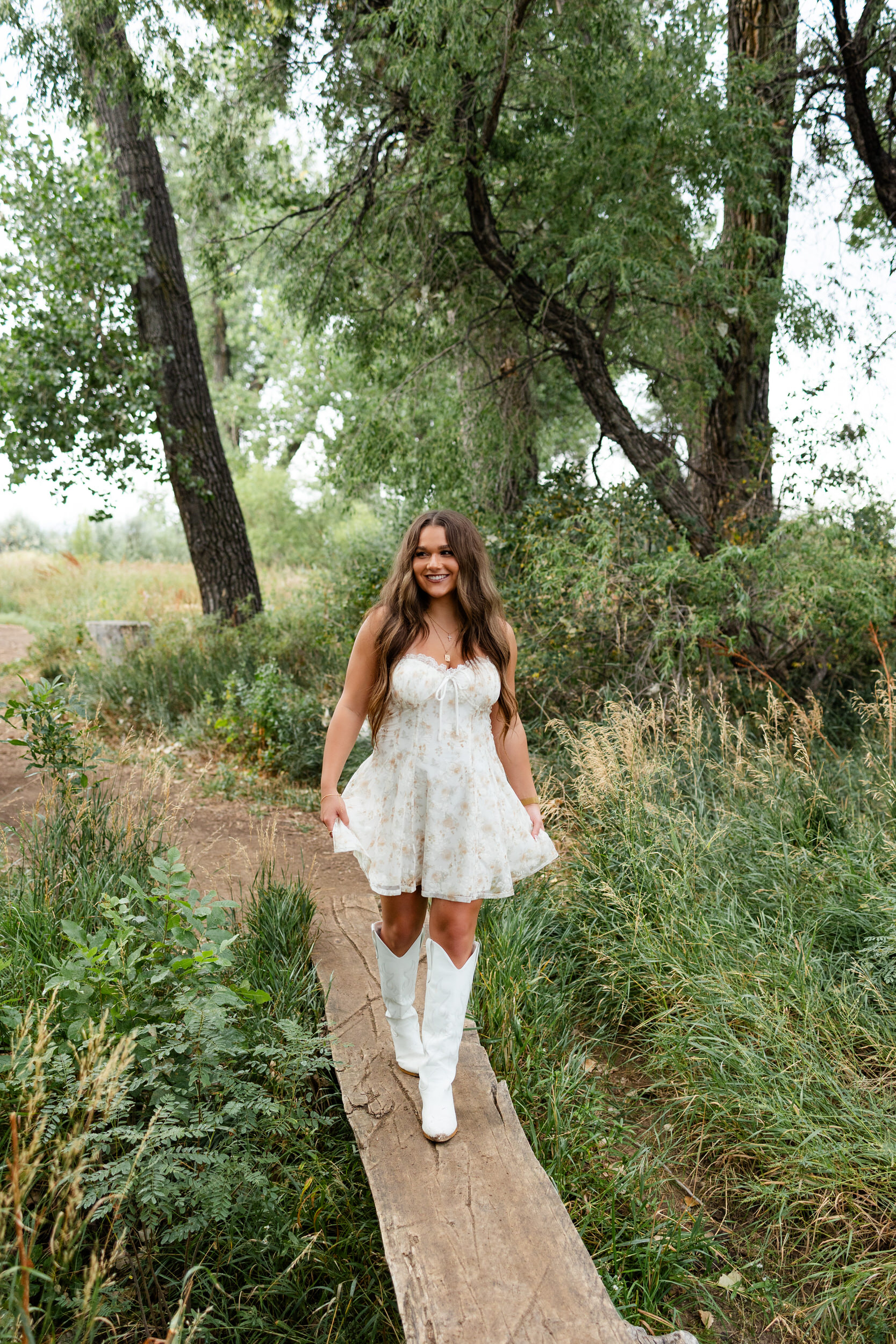A young woman walks across a log bridge.