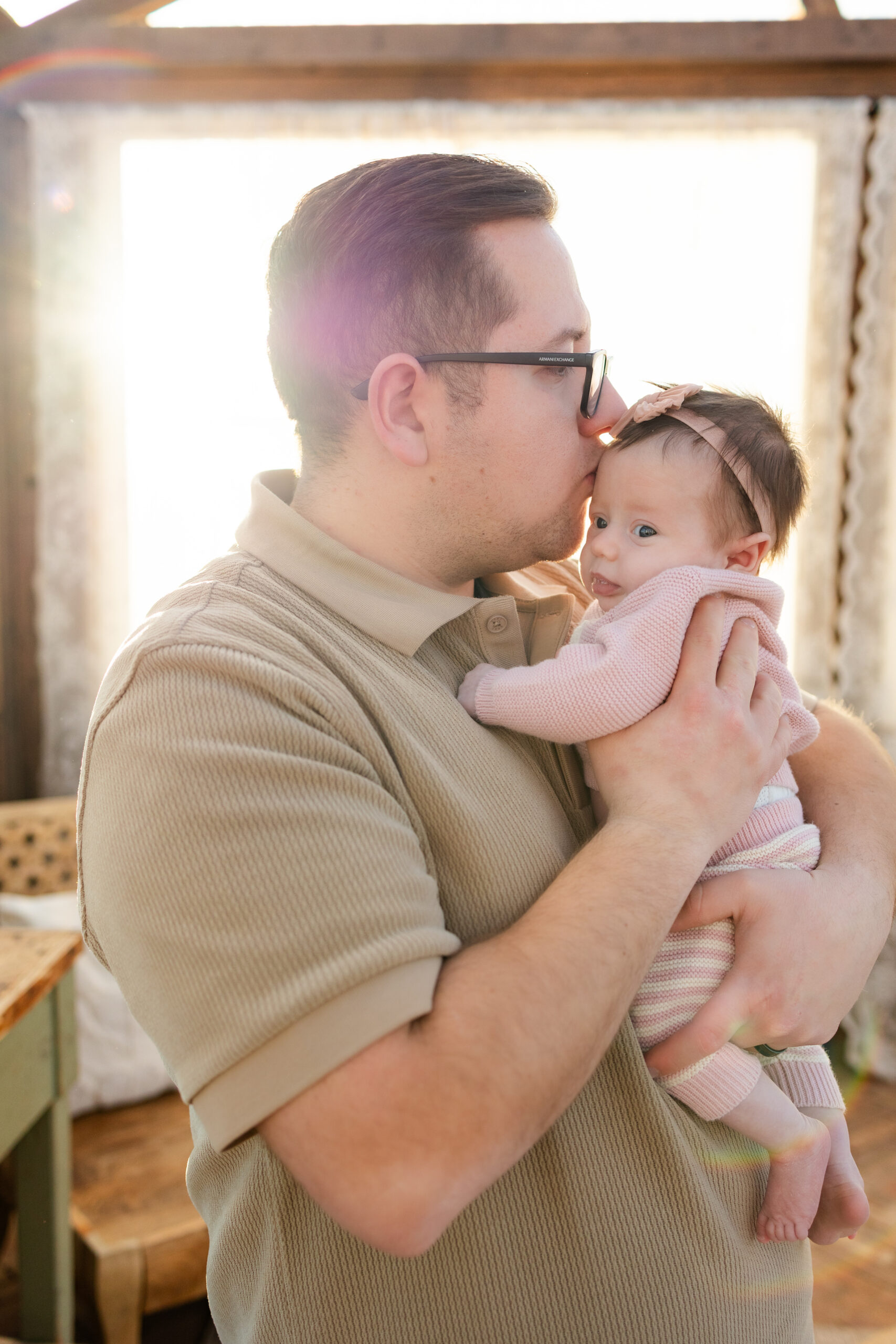 Dad holds newborn baby girl and kisses her head.