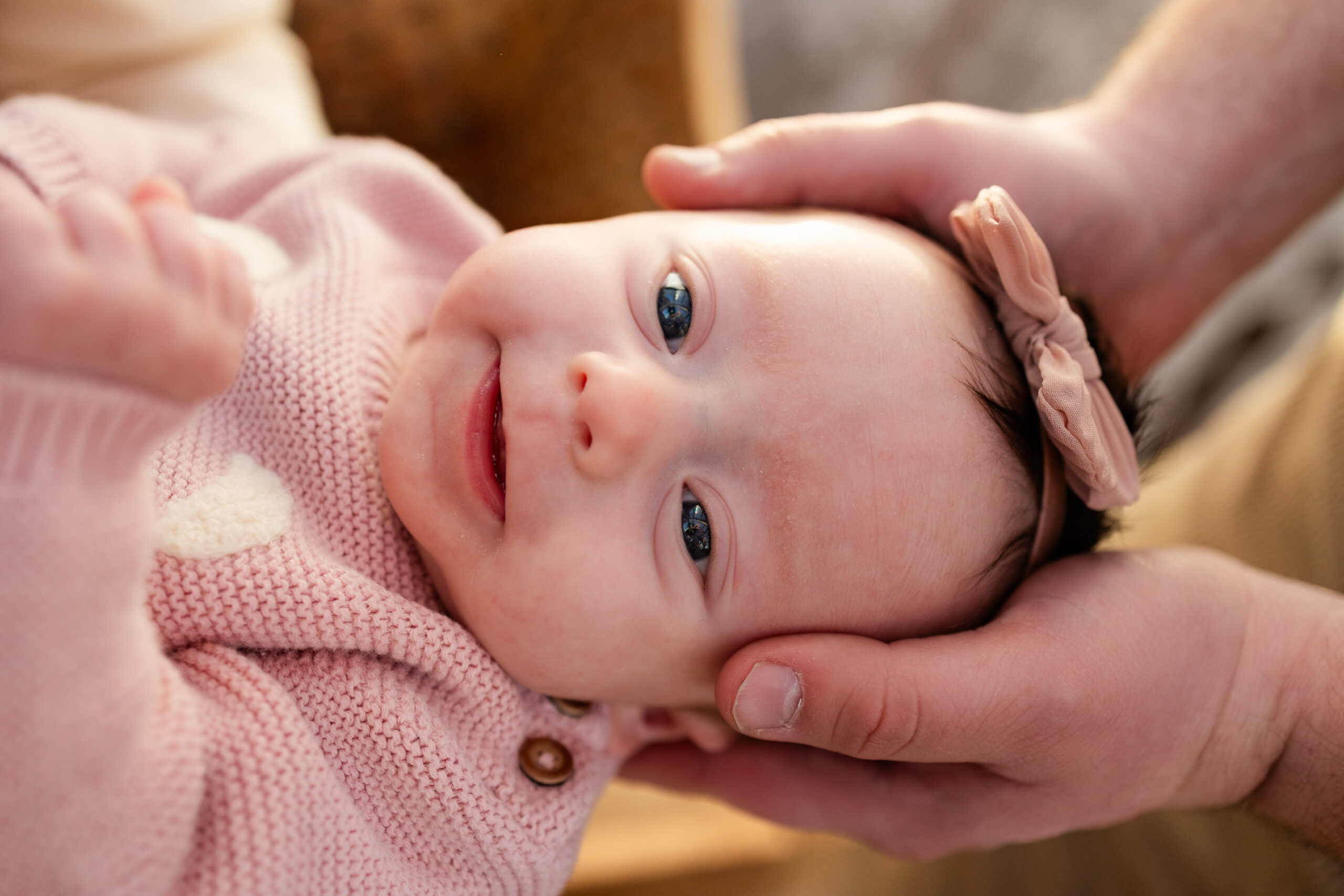 Dad holds newborn baby girl's head in his hands.