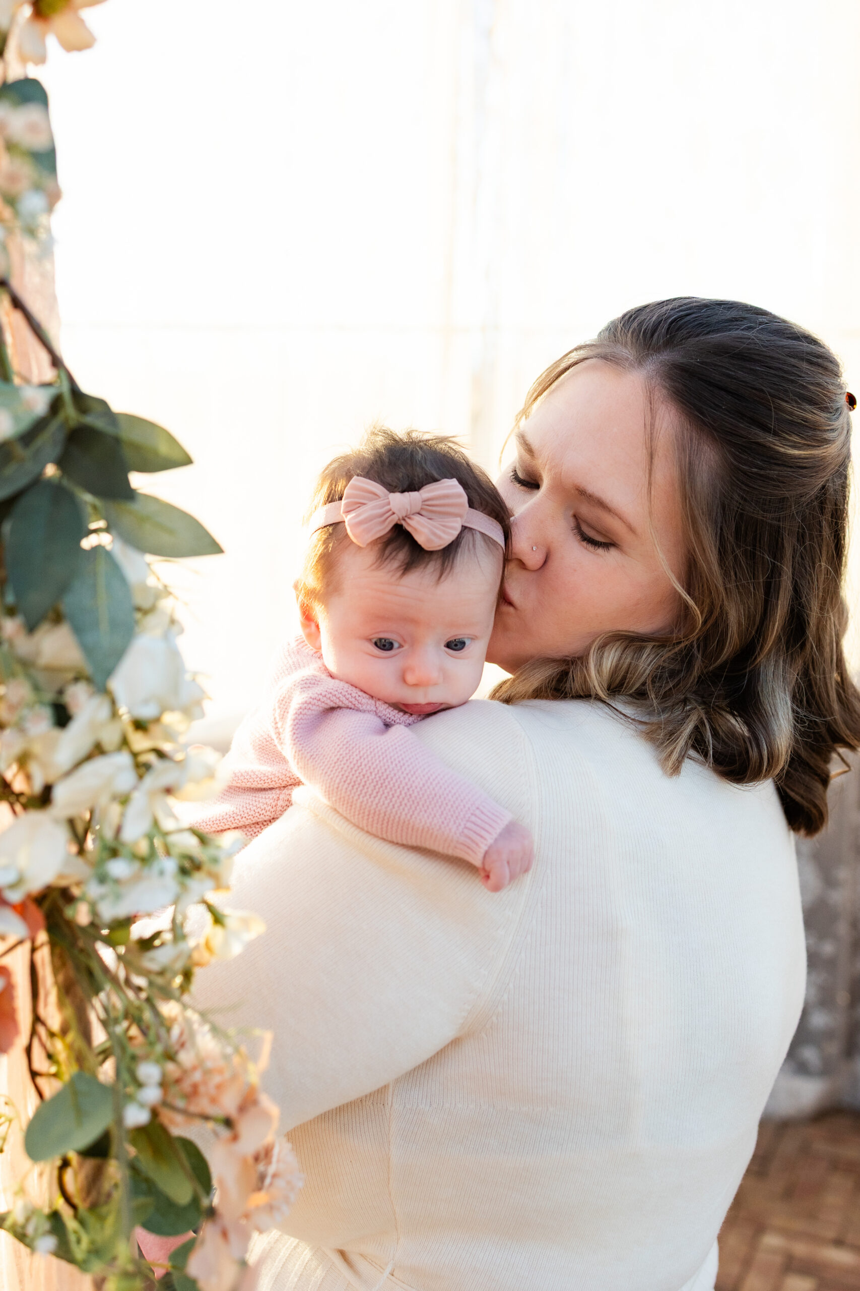 Mom kisses newborn daughter's head.