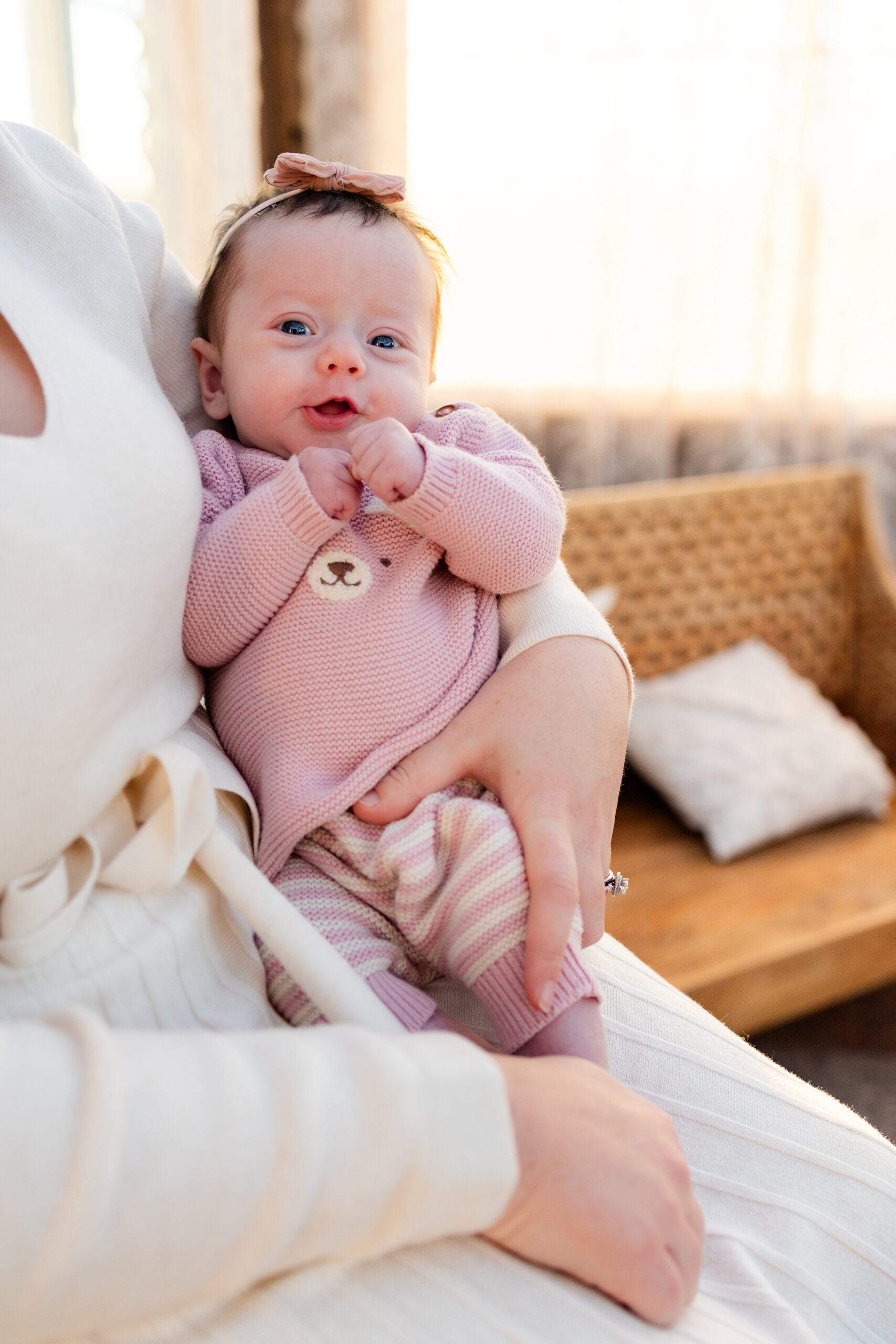 Newborn girl smiles at the camera while resting in her mother's arms.