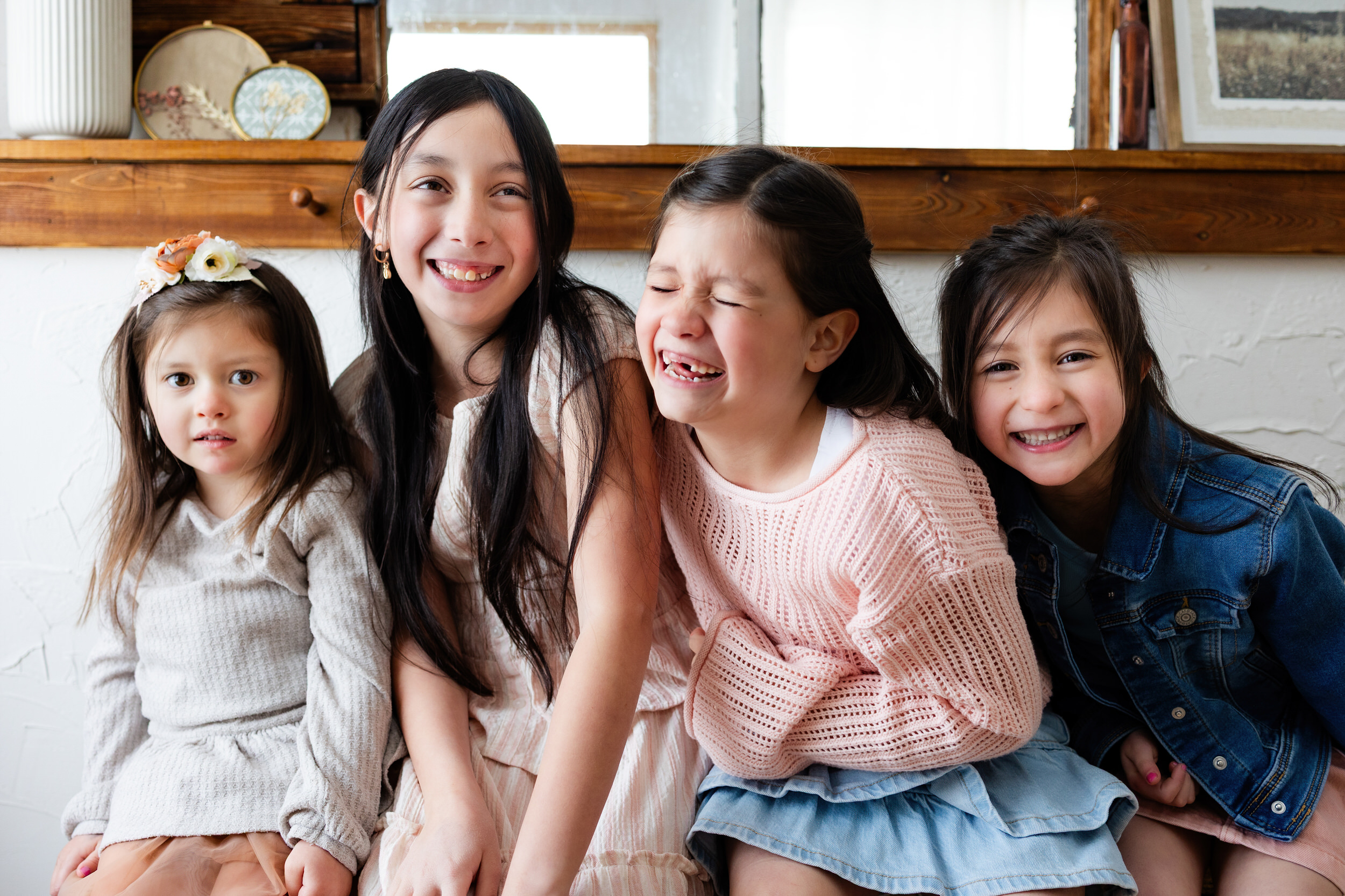 Four sisters sit on a bench in a cottage and laugh.