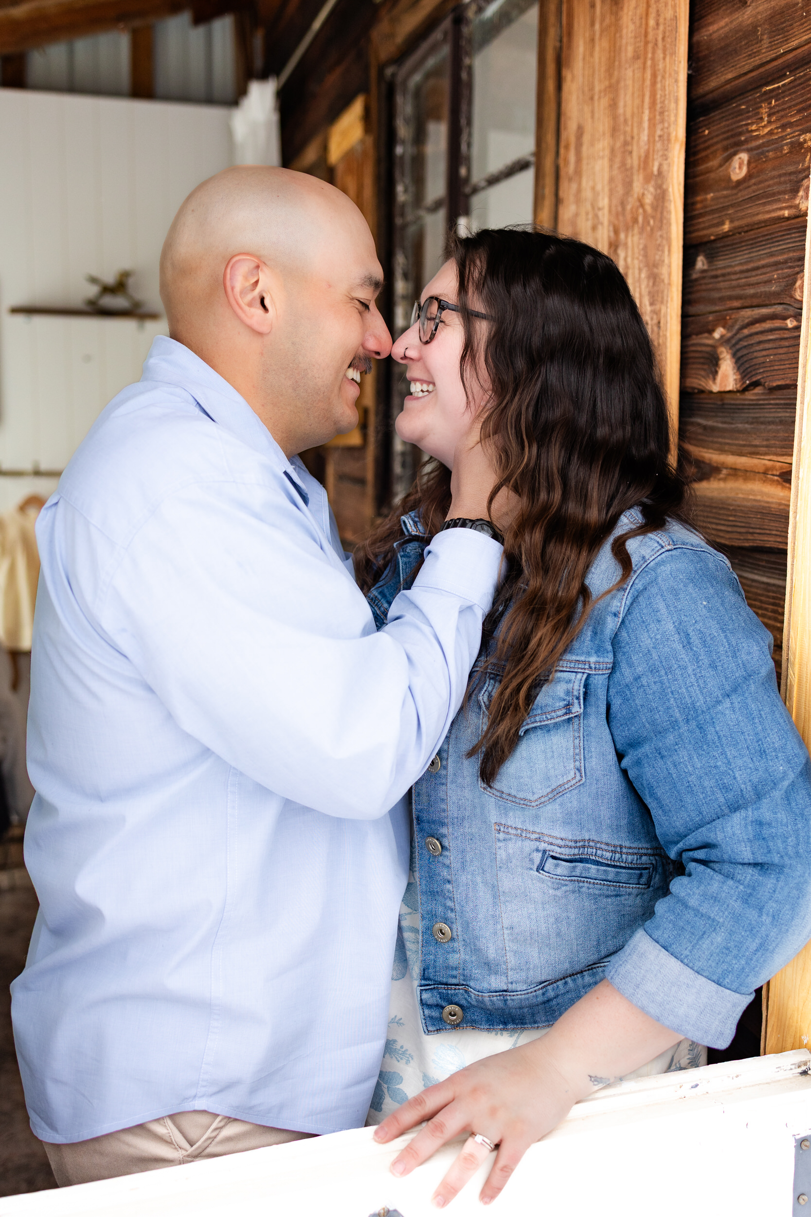 Husband and wife stand nose-to-nose and smile at each other.