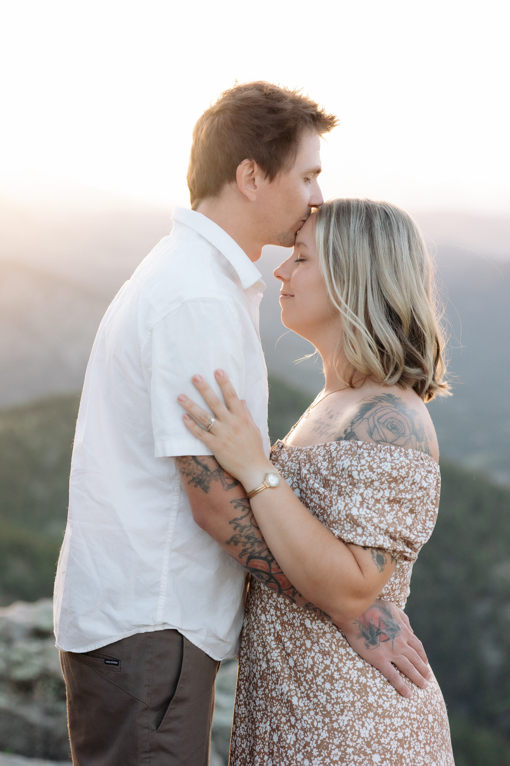 Husband kisses his wife's forehead during their anniversary photoshoot at Lost Gulch Overlook.