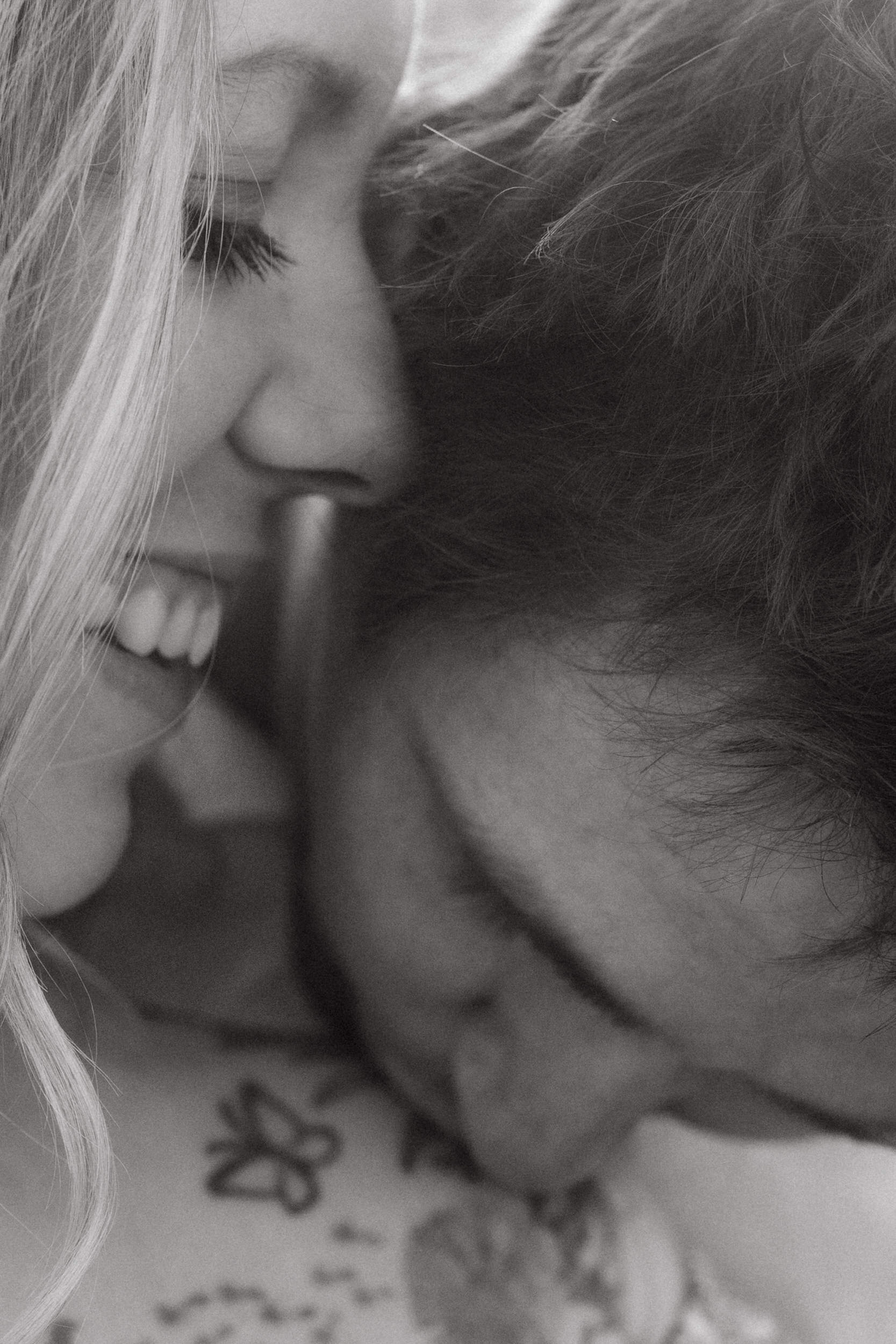 Husband kisses wife's shoulder as she smiles at him.