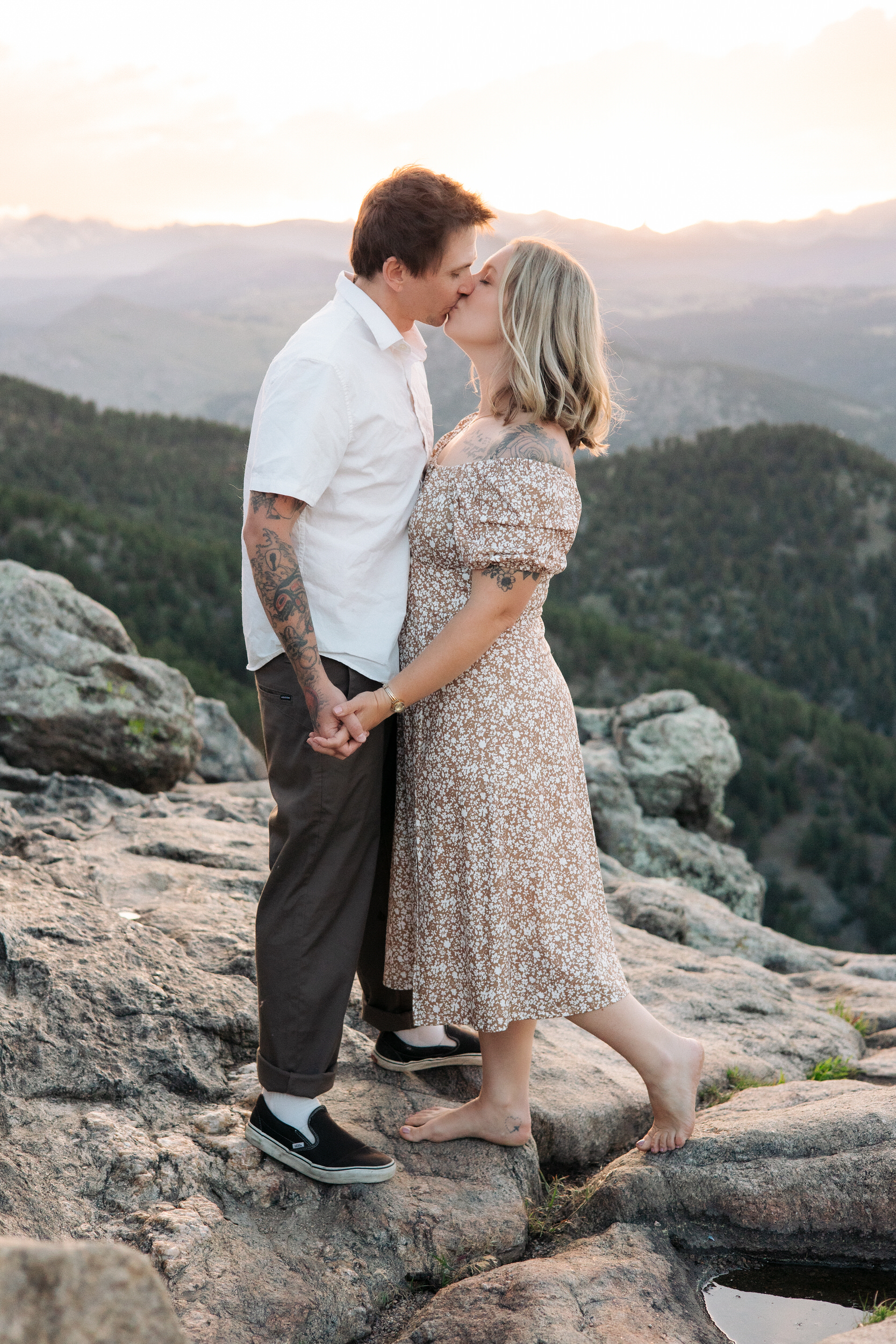 Husband and wife share a kiss with sweeping mountain views behind them at Lost Gulch Overlook in Boulder, Colorado.